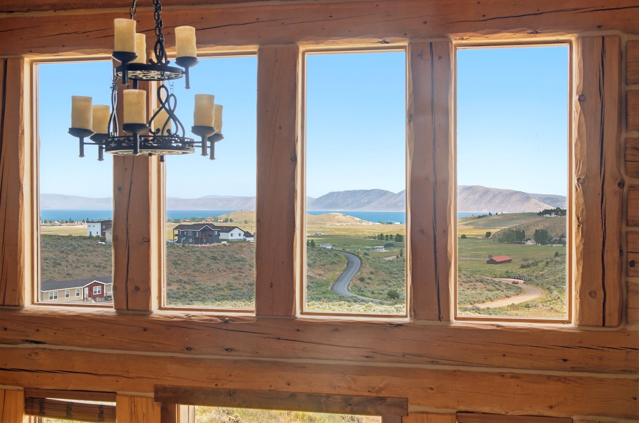 Timber frame construction featuring a rustic chandelier and multiple large windows