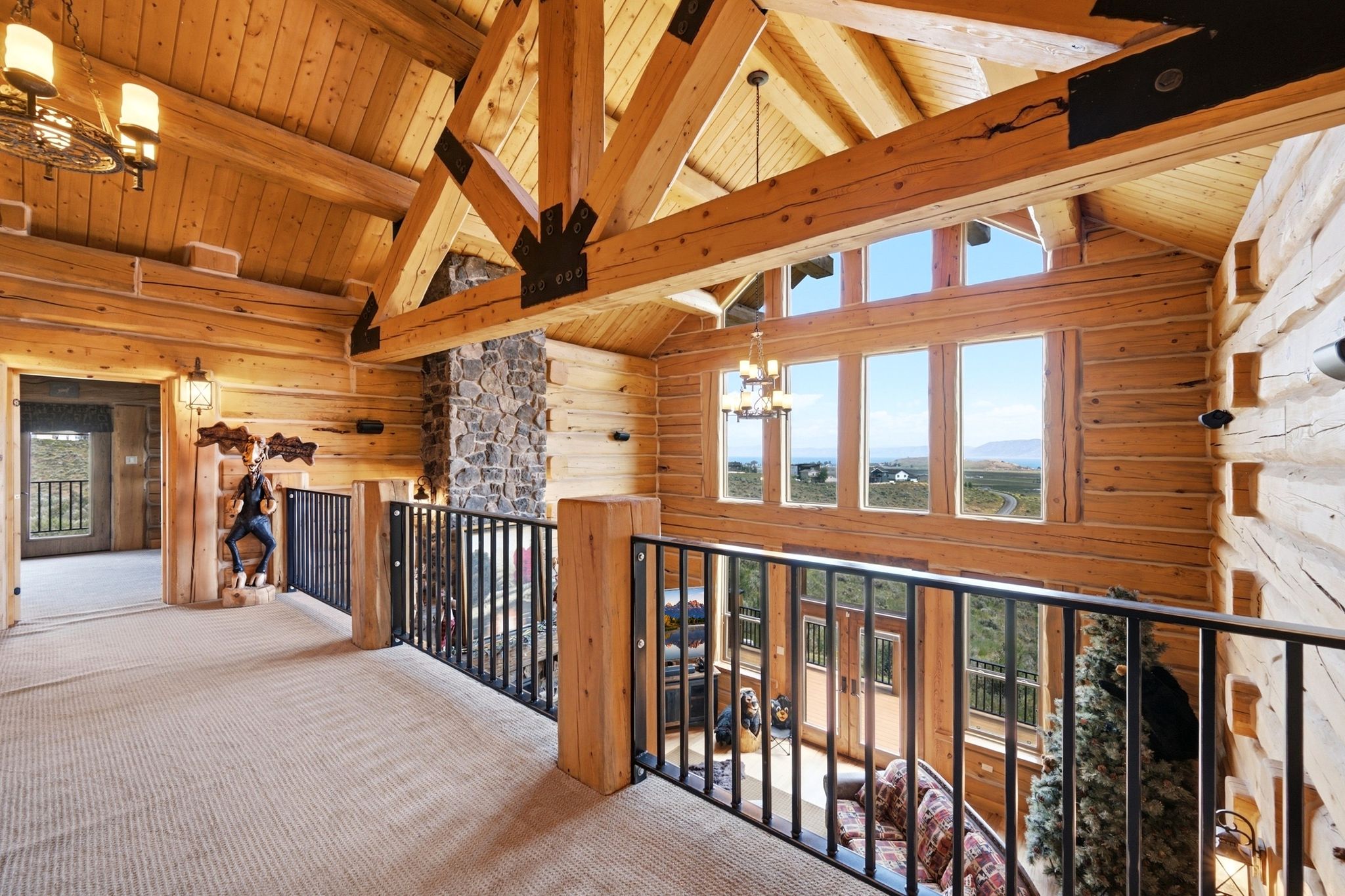 Loft area showcasing exposed wood beams, log walls, and a stone-clad fireplace