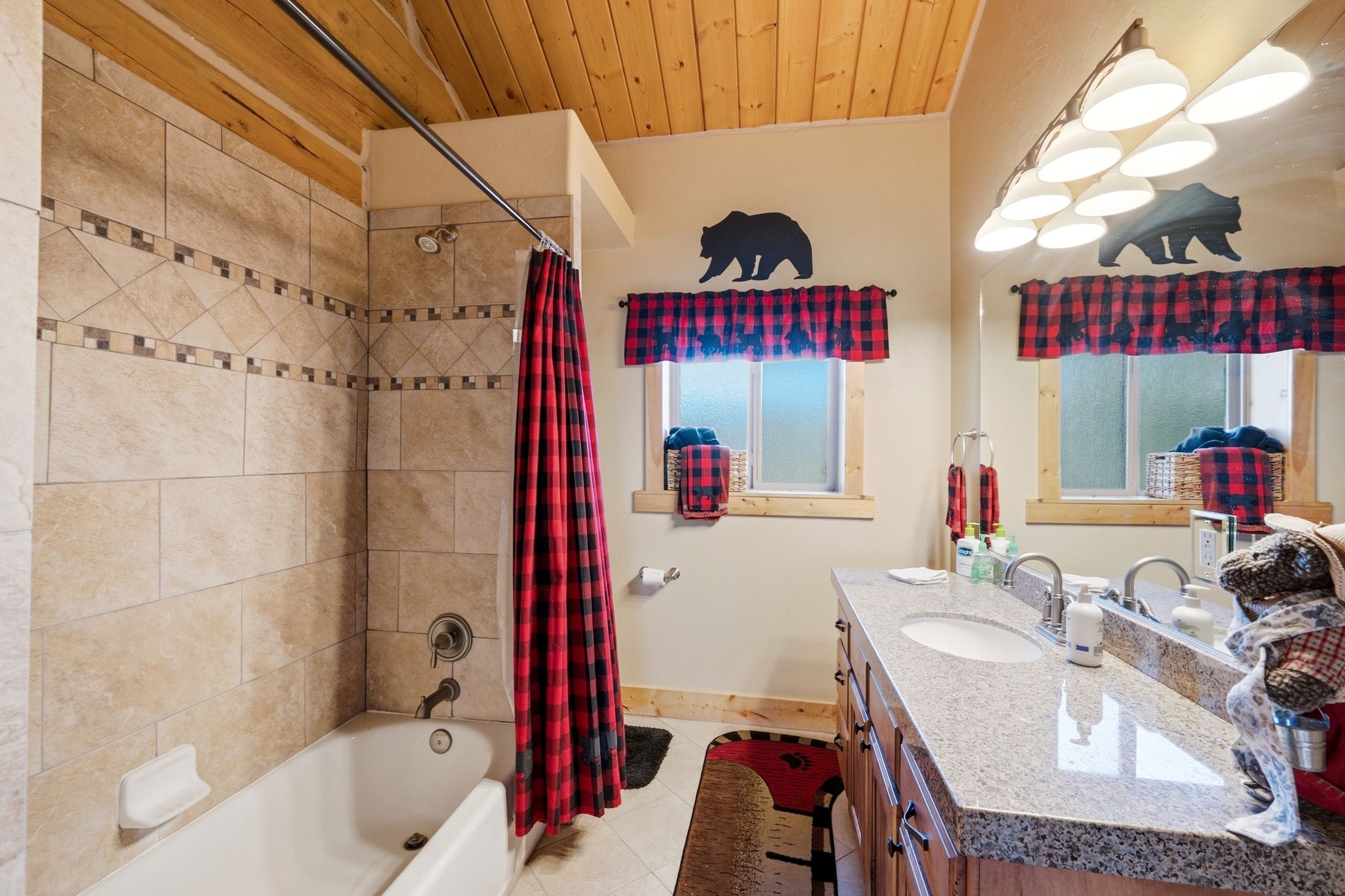 Bathroom featuring a dual vanity with granite countertop, wood-finish cabinetry, and two integrated sinks