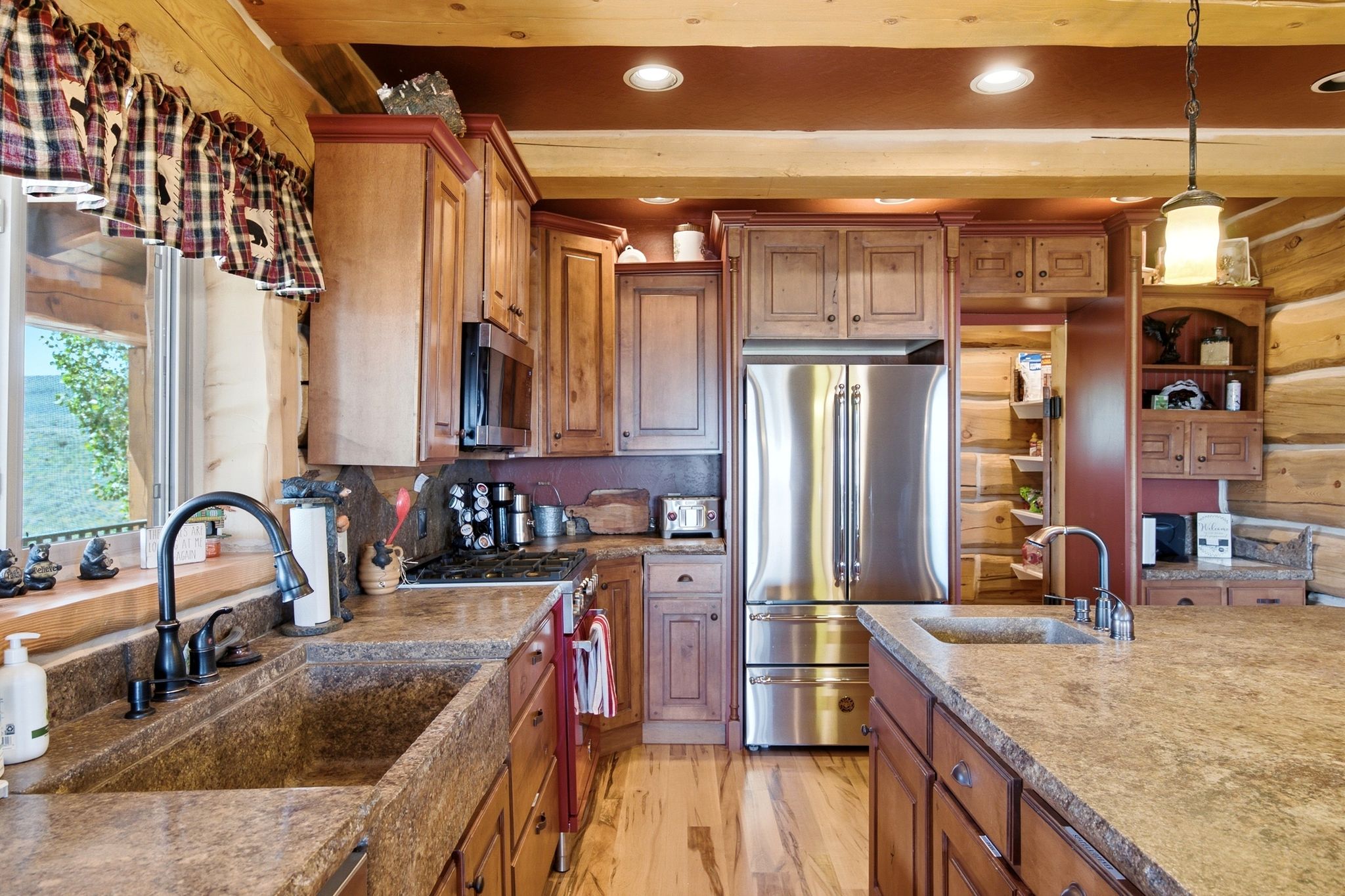 Kitchen featuring custom wood cabinetry, stone countertops, stainless steel appliances, a built-in pantry, and wood-finish flooring