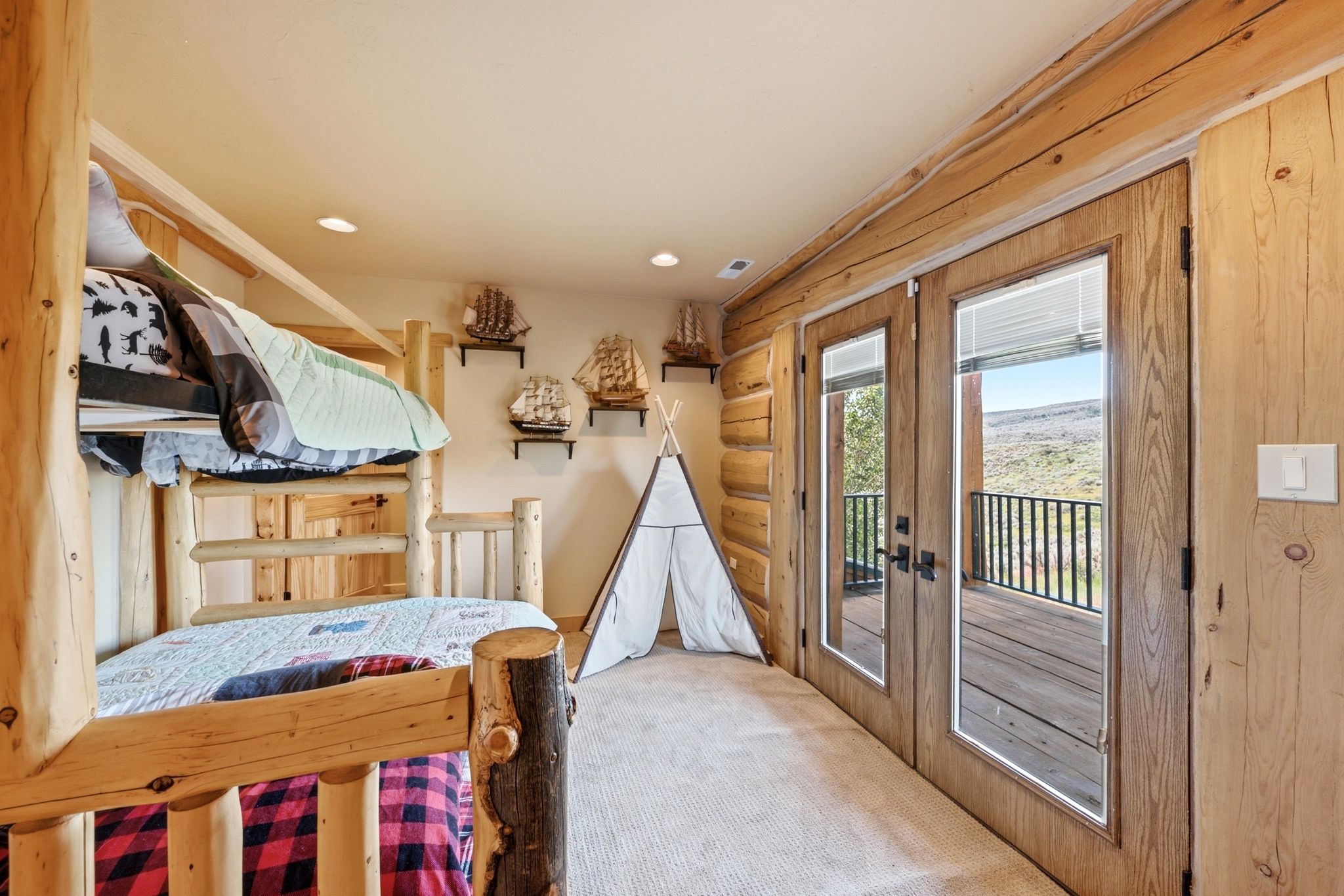 Light wood-paneled room featuring a built-in bunk bed with log-style posts, recessed ceiling lighting, and a neutral-toned carpet