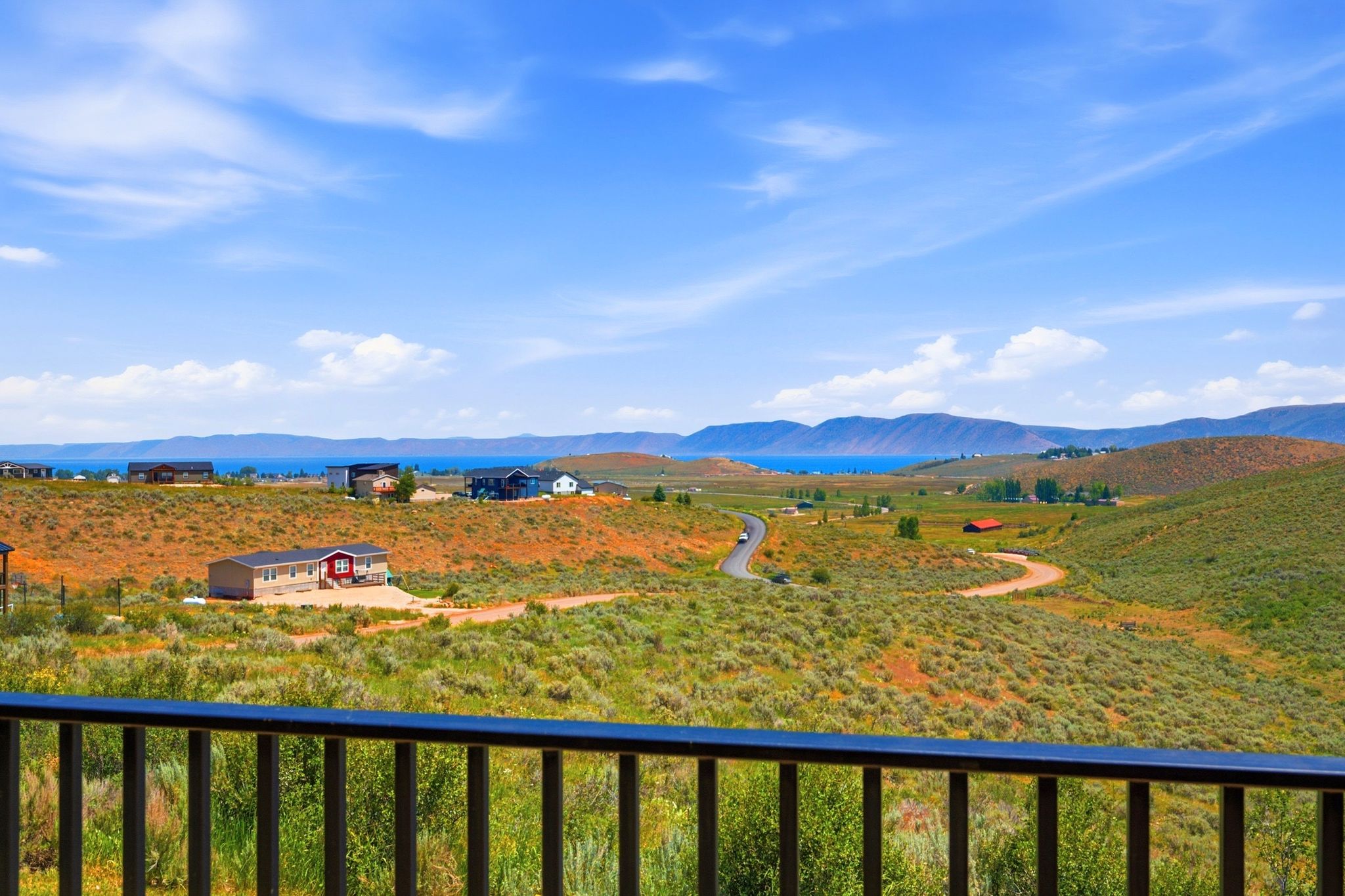 Expansive landscape featuring distant water, undulating hills, and scattered residences