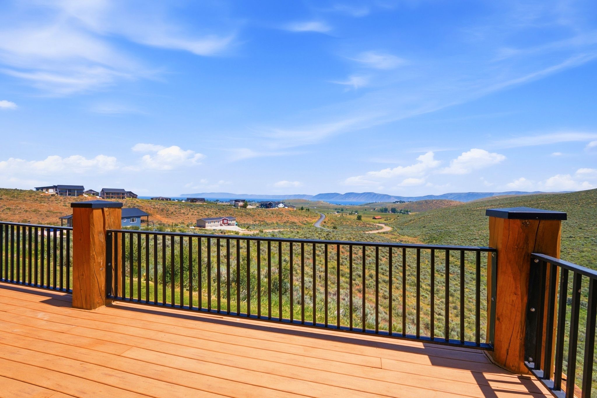 Spacious outdoor deck with natural wood-tone flooring and a black metal railing system