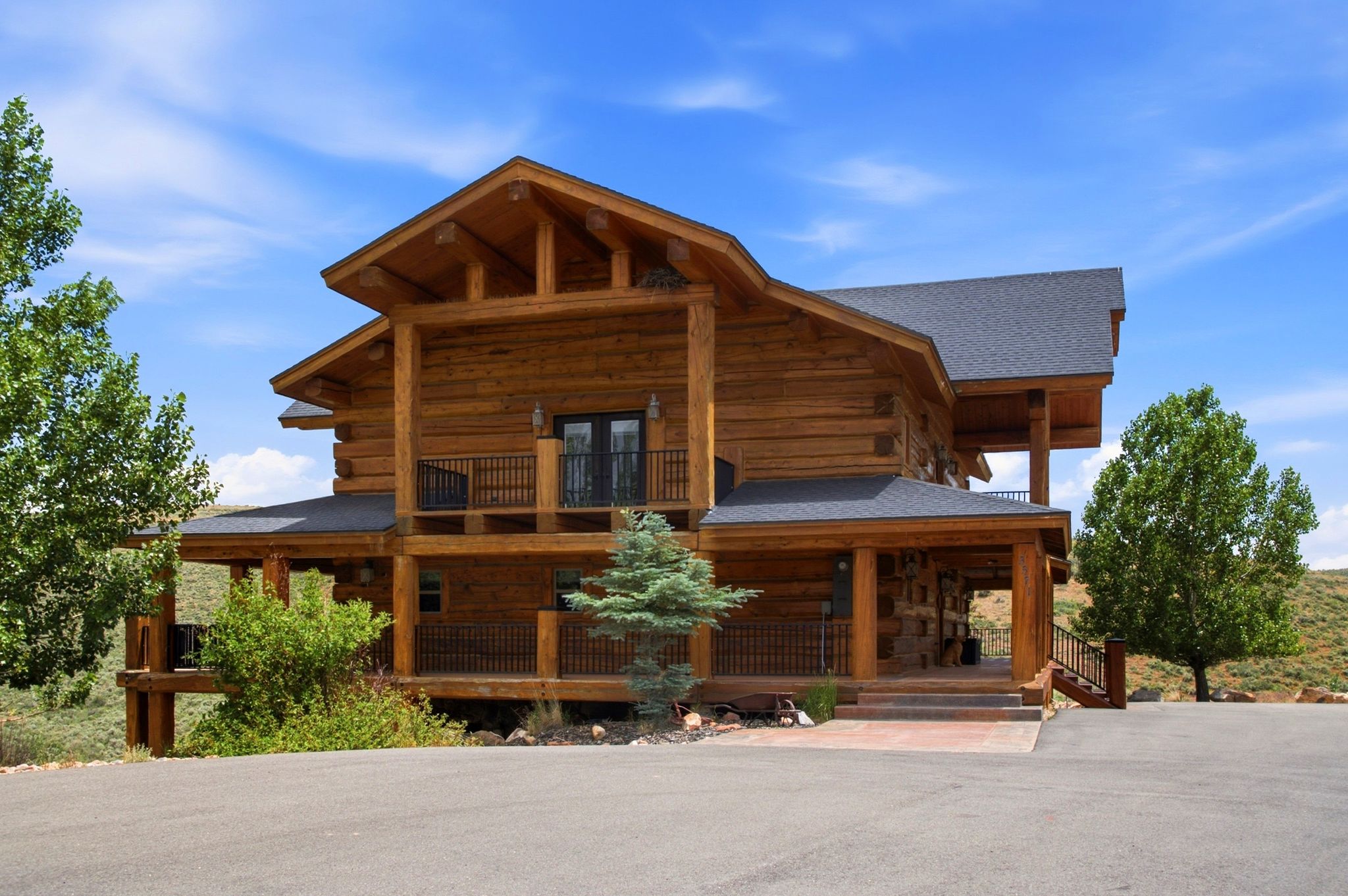 Log-style exterior featuring multiple levels of covered porches and balconies with black railing