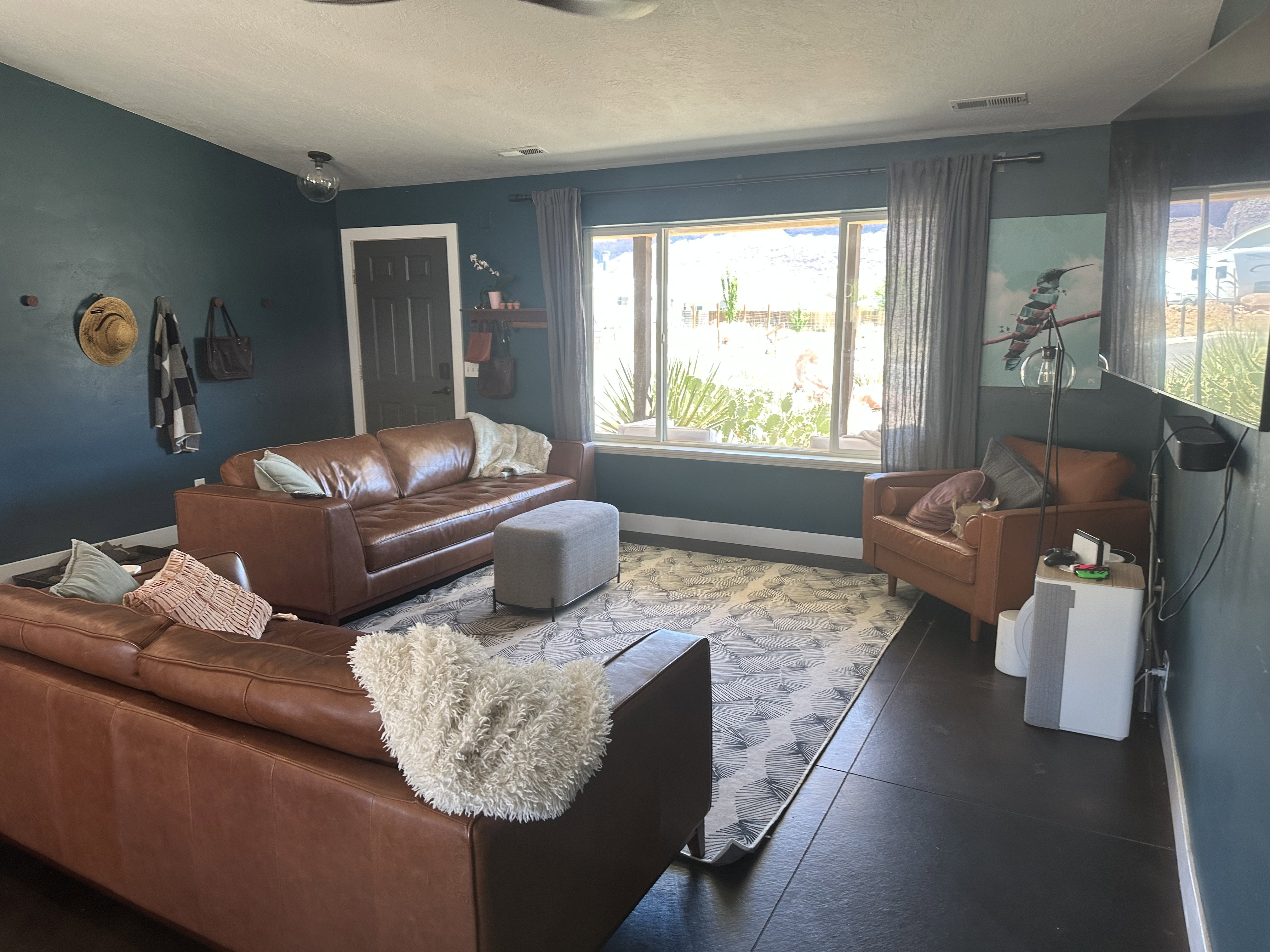Spacious living area with large window, vaulted ceiling with fan and stained concrete flooring