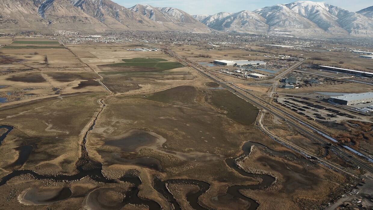 Expansive aerial perspective showcasing diverse terrain with a meandering waterway, agricultural fields, and developed areas