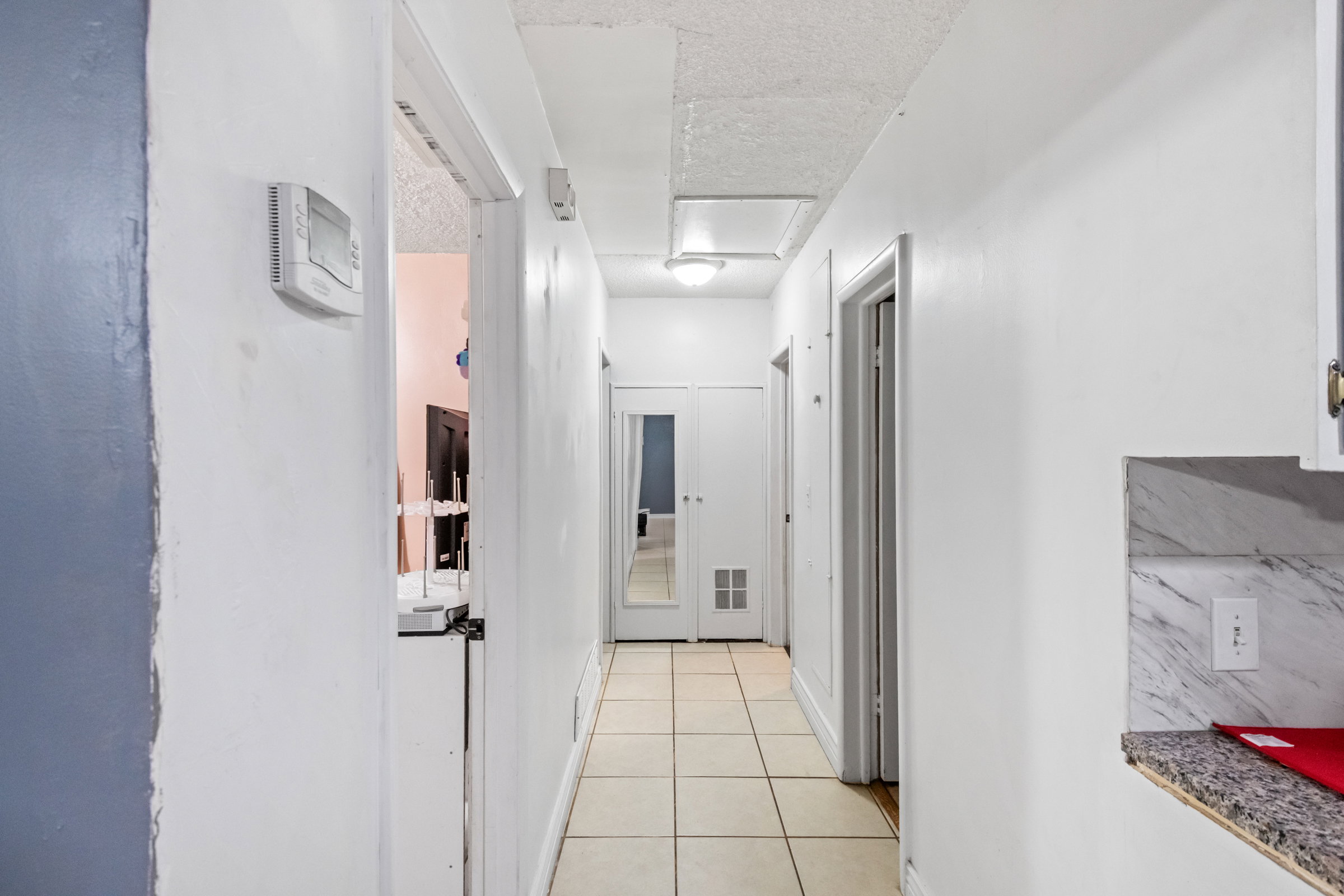 Hallway featuring tile flooring, white walls, and recessed lighting
