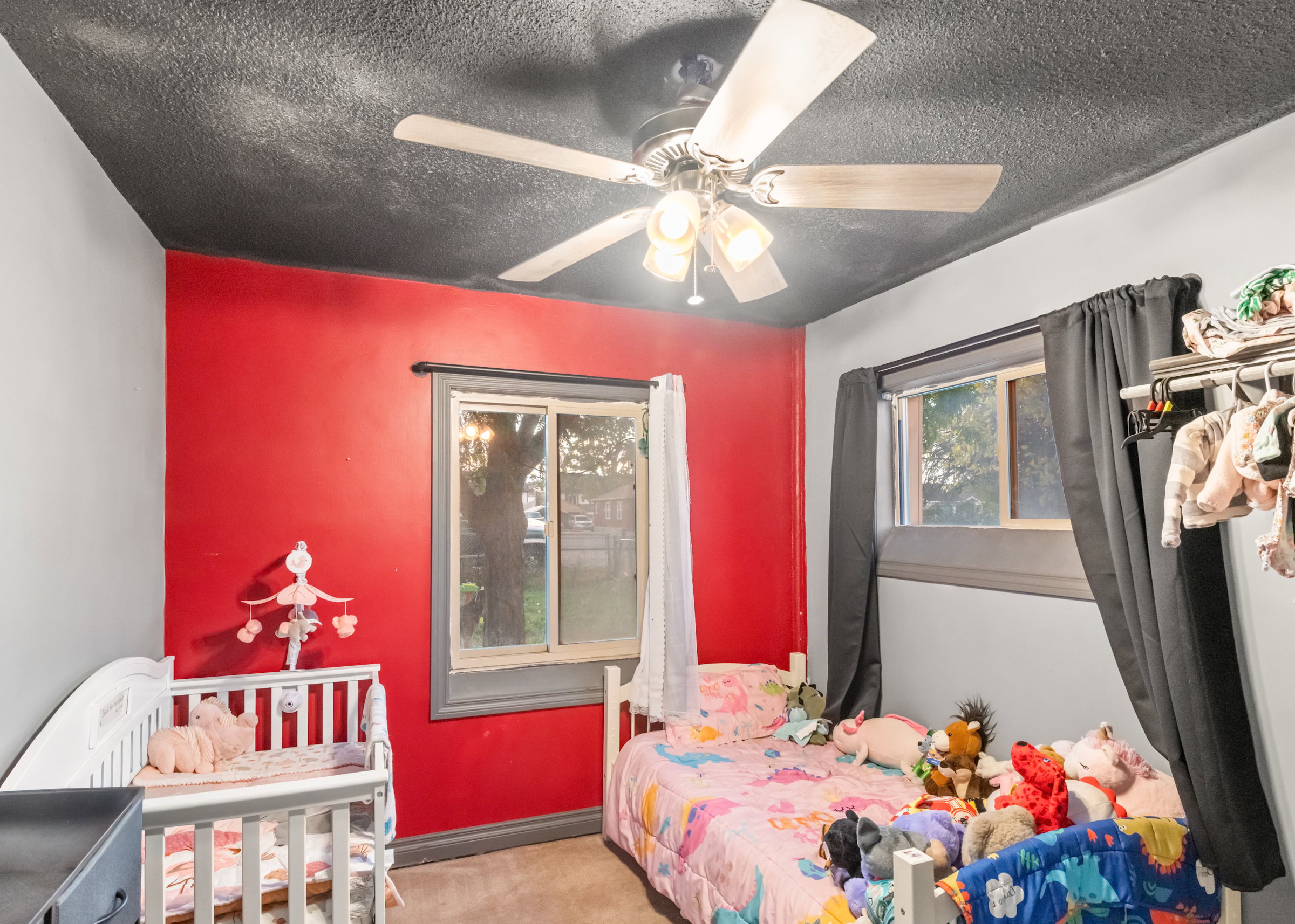 Interior room featuring a ceiling fan with light kit, a window with grey trim, and a red accent wall