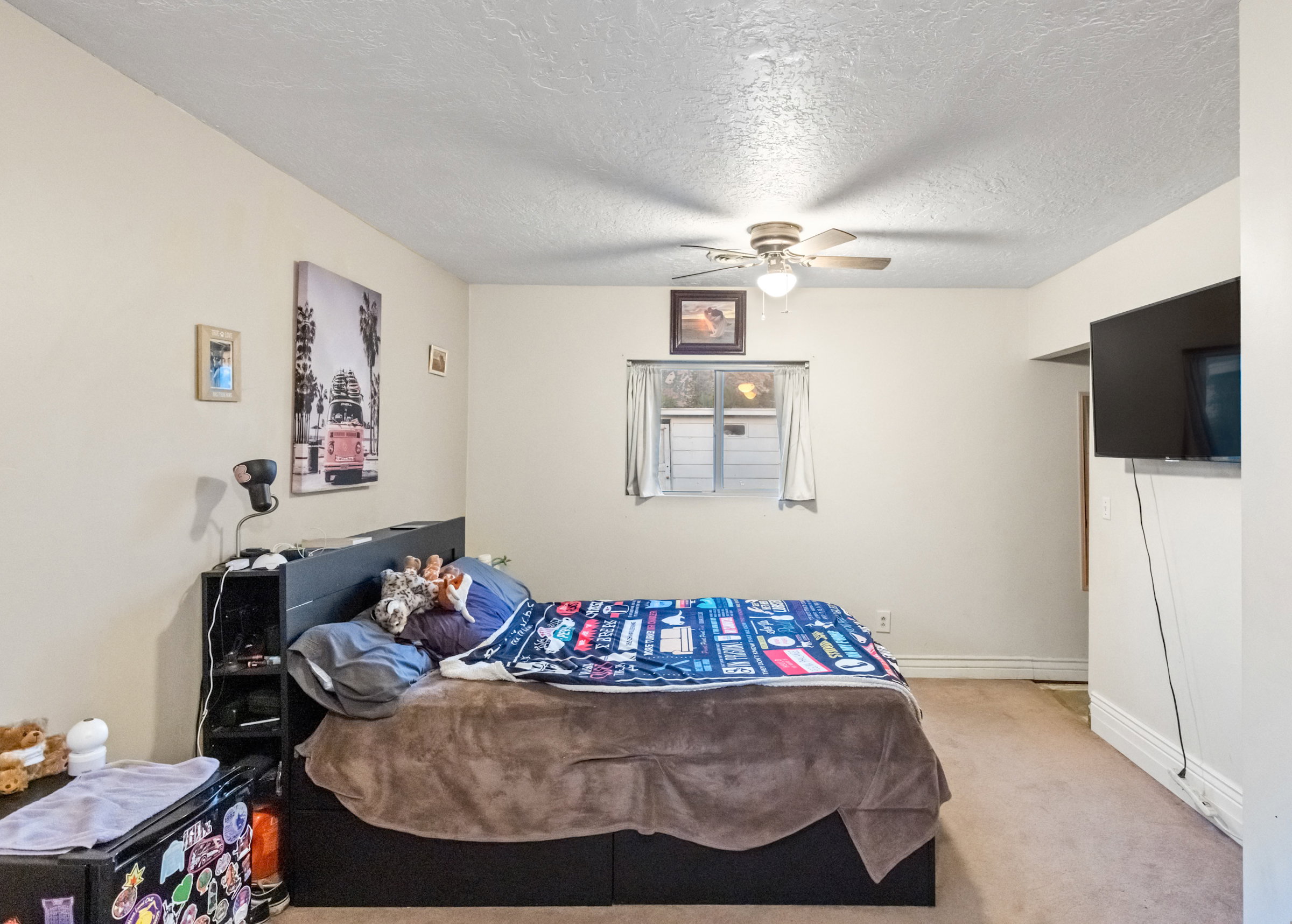 Carpeted interior room featuring a window with a built-in air conditioning unit, a ceiling fan with integrated lighting, and light-colored walls