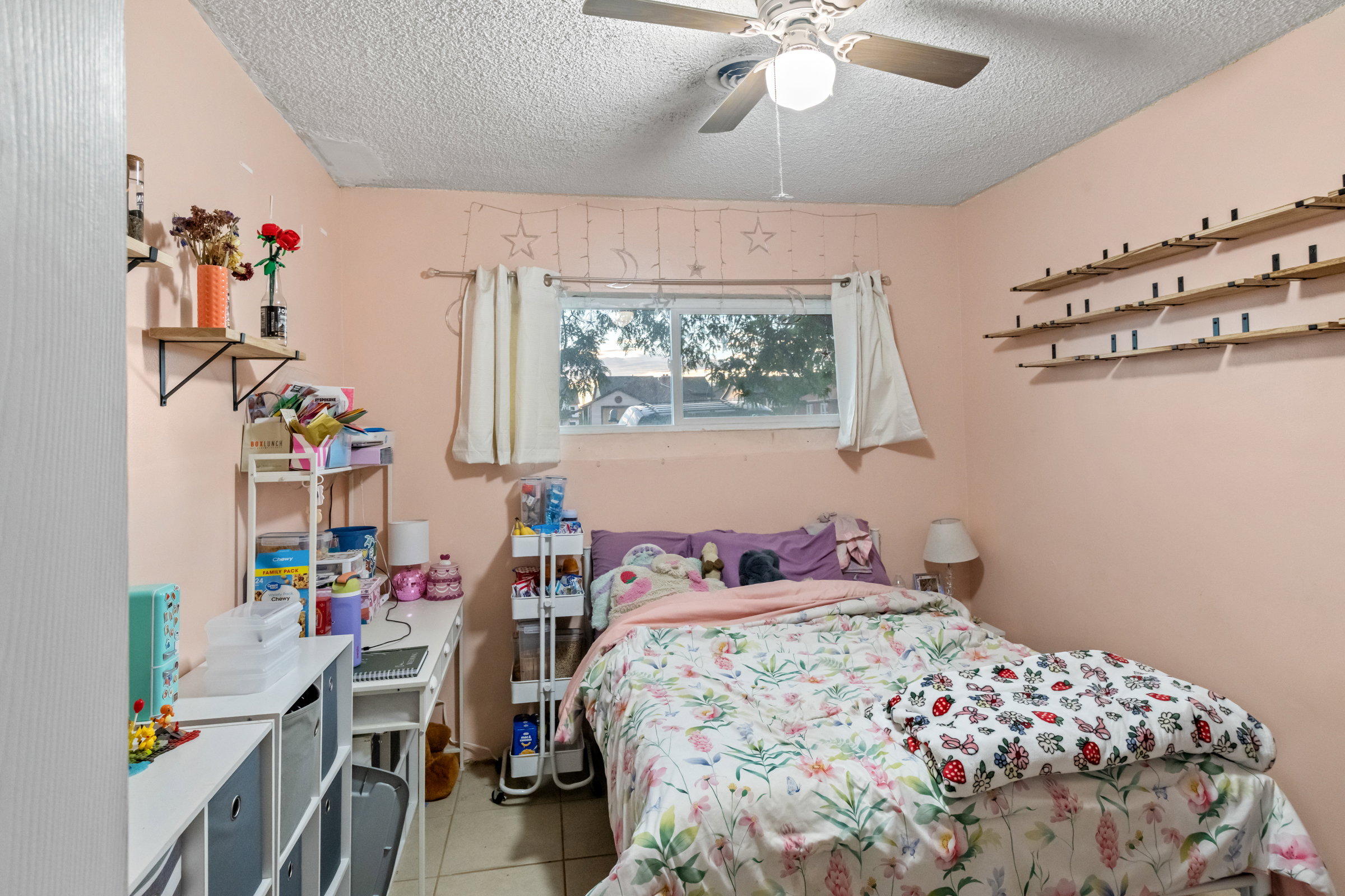 Bedroom featuring a ceiling fan, a window with exterior views, and tiled flooring