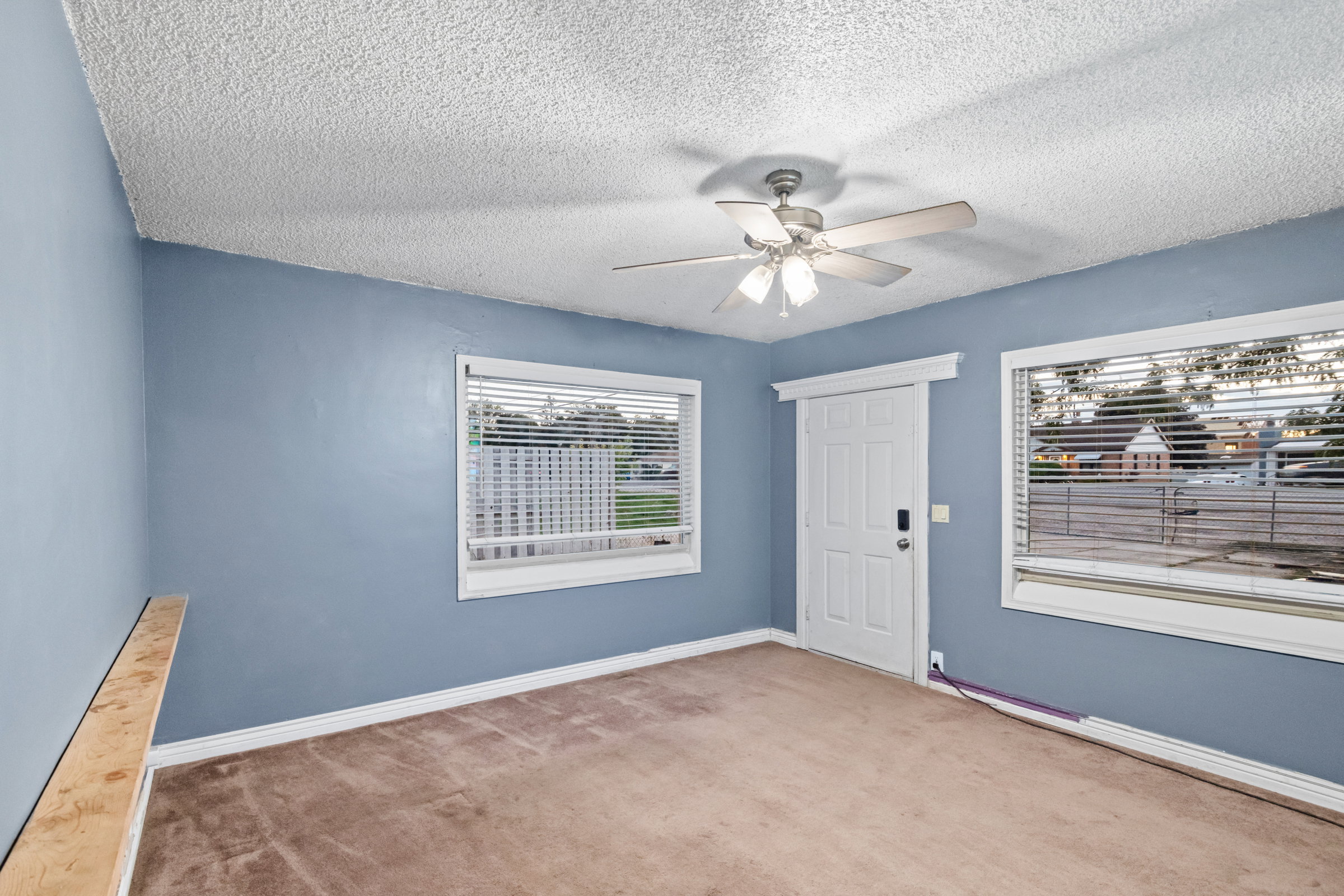 Room featuring light blue walls, a textured ceiling, and neutral-toned carpeting