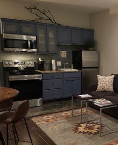 Compact kitchen featuring blue cabinetry, stainless steel appliances, granite-look countertops, and tile flooring