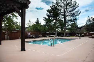 Outdoor swimming pool with integrated water features, surrounded by a light-colored concrete deck