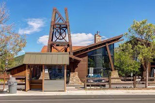 Distinctive architectural facade featuring a prominent mining-themed tower, expansive window walls, natural wood siding, stone accents, and an angular roofline