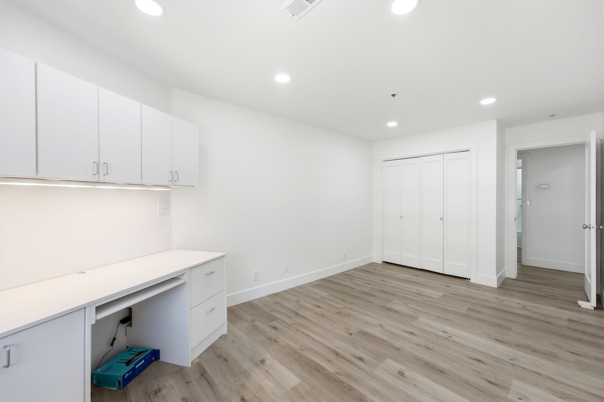 Spacious second bedroom with Dedicated workspace featuring built-in white cabinetry, under-cabinet lighting, and a desk area