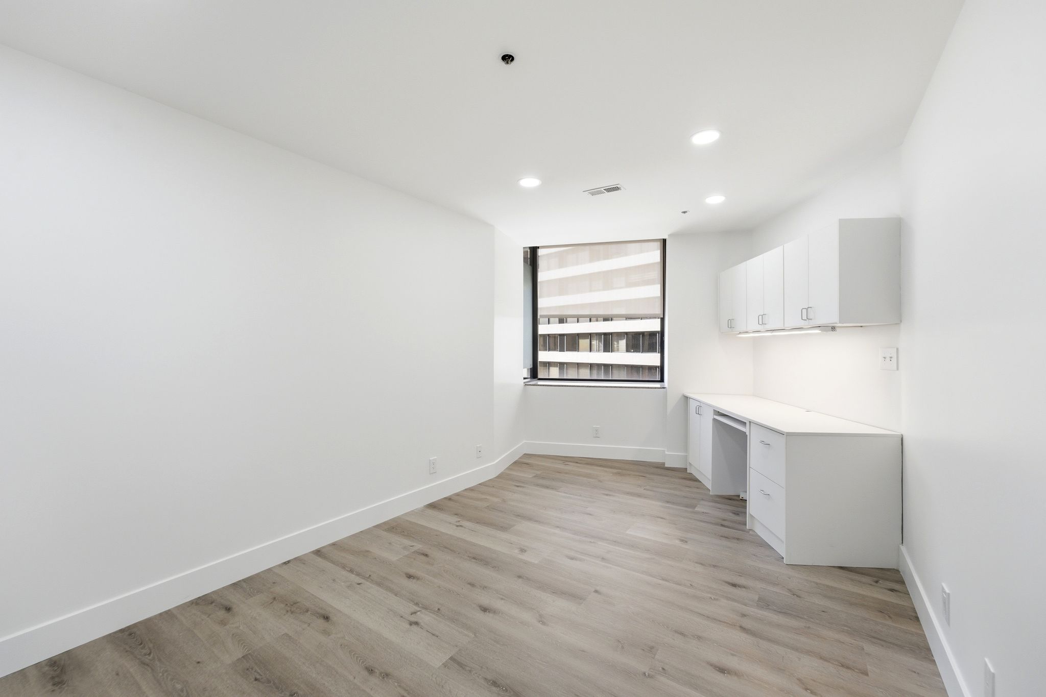 Second bedroom feat. Built-in desk with overhead cabinetry, recessed lighting, and wood-finish flooring