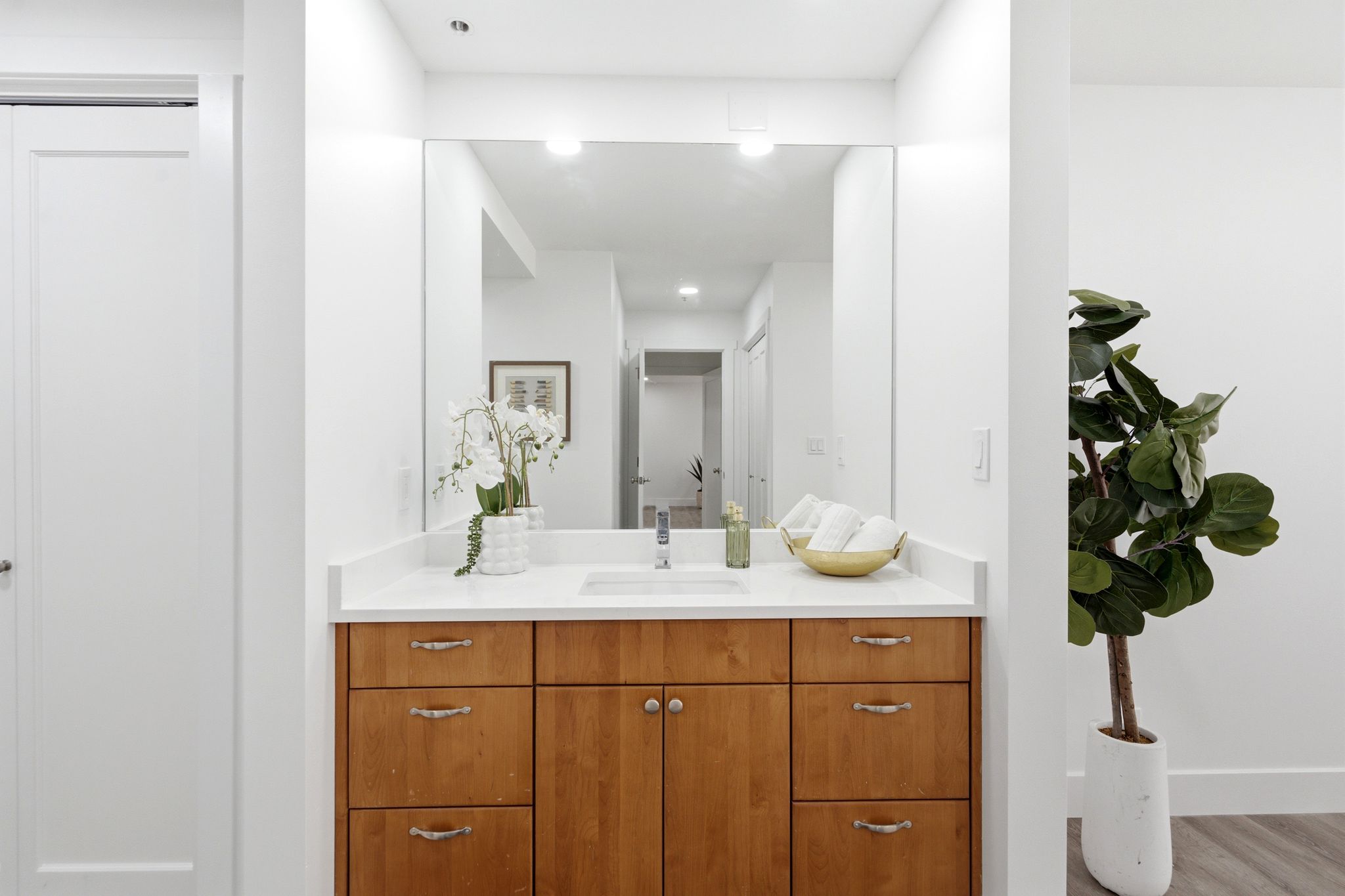 Master Bathroom vanity featuring a light wood-finish cabinet with varied drawer and door configurations, a white countertop, and an integrated rectangular sink