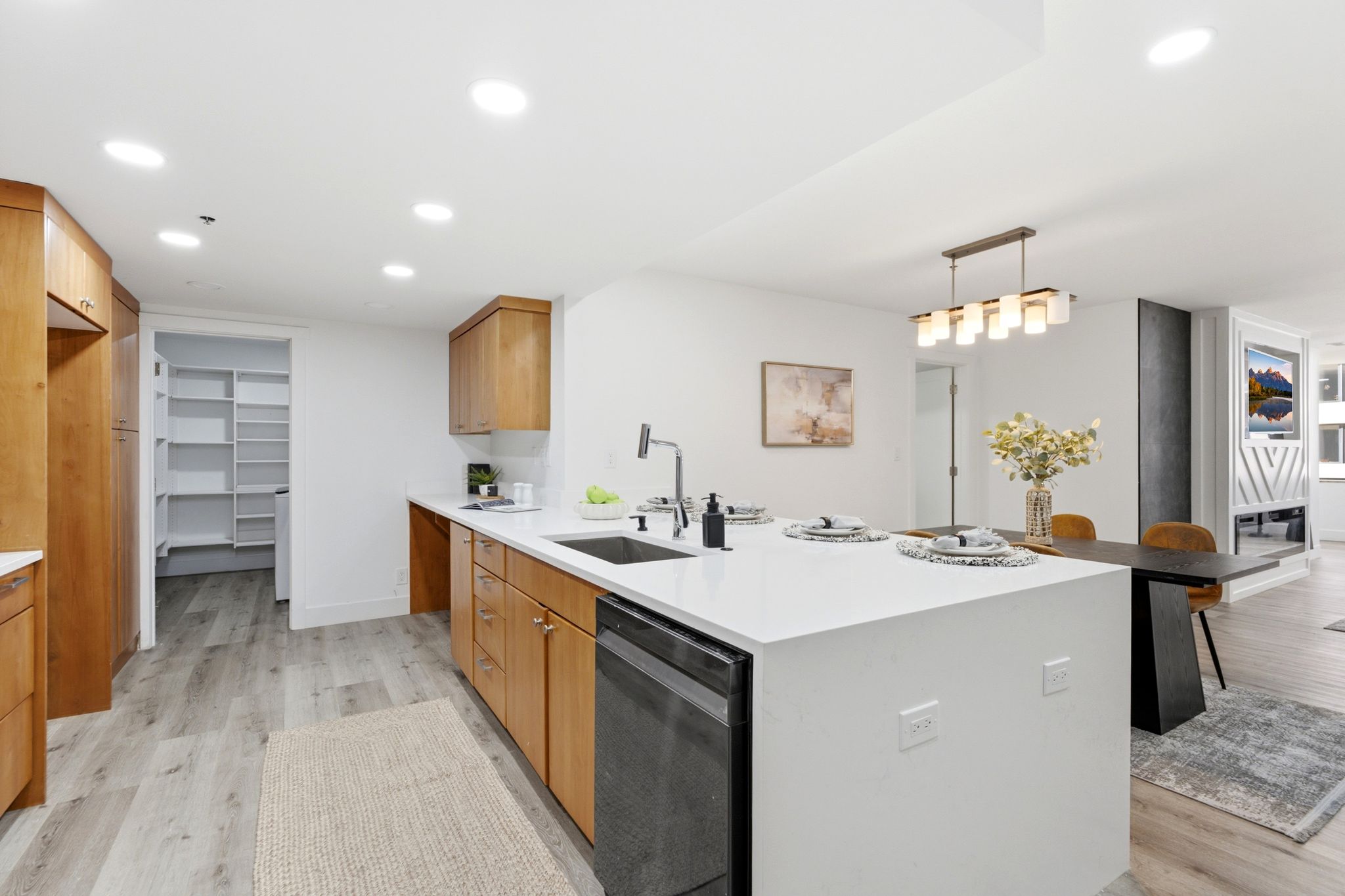 Contemporary kitchen featuring wood cabinetry, light-toned flooring, and a spacious center island with an integrated sink and dishwasher