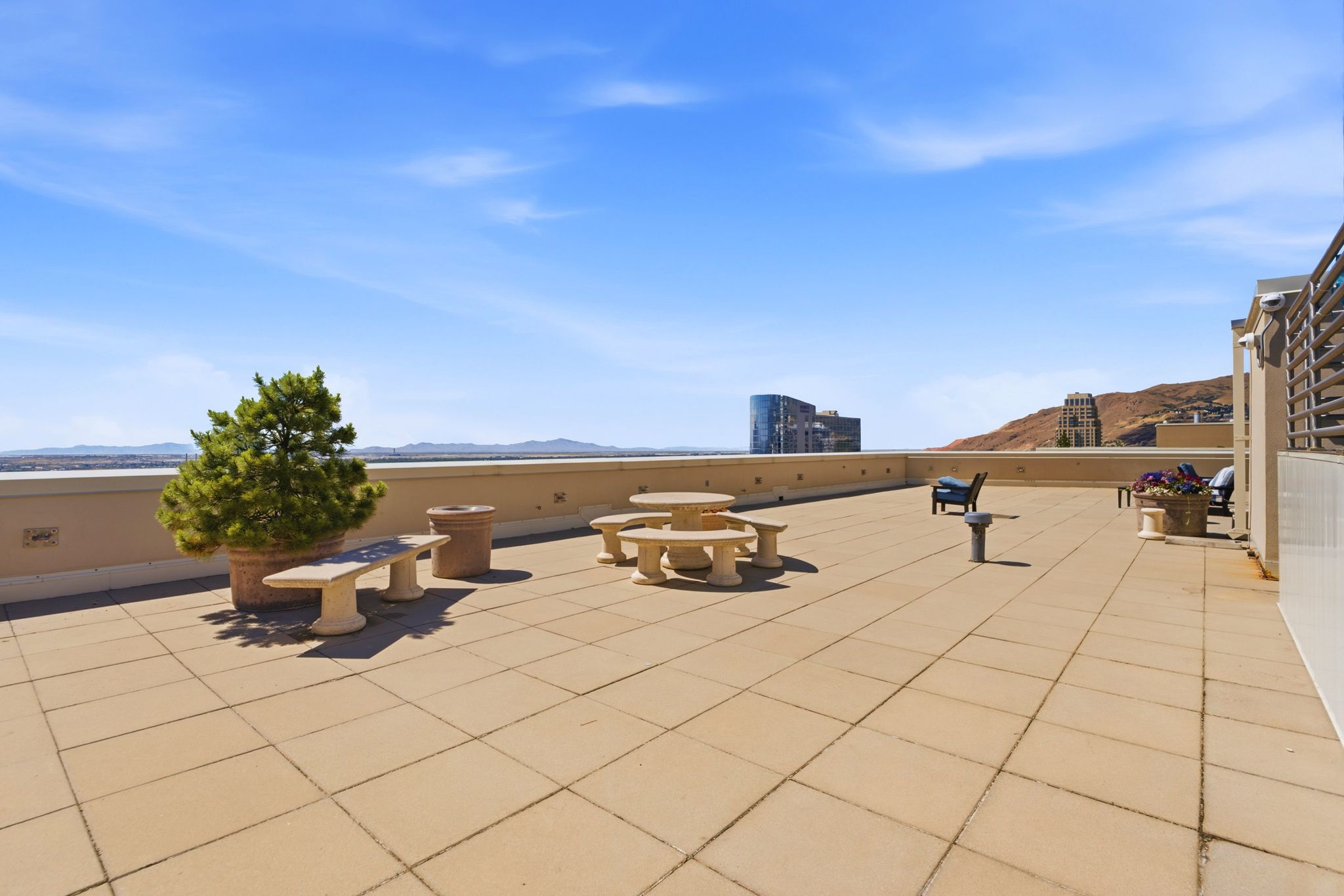 Expansive rooftop terrace featuring large format tile flooring, a low perimeter wall, and distant mountain scenery