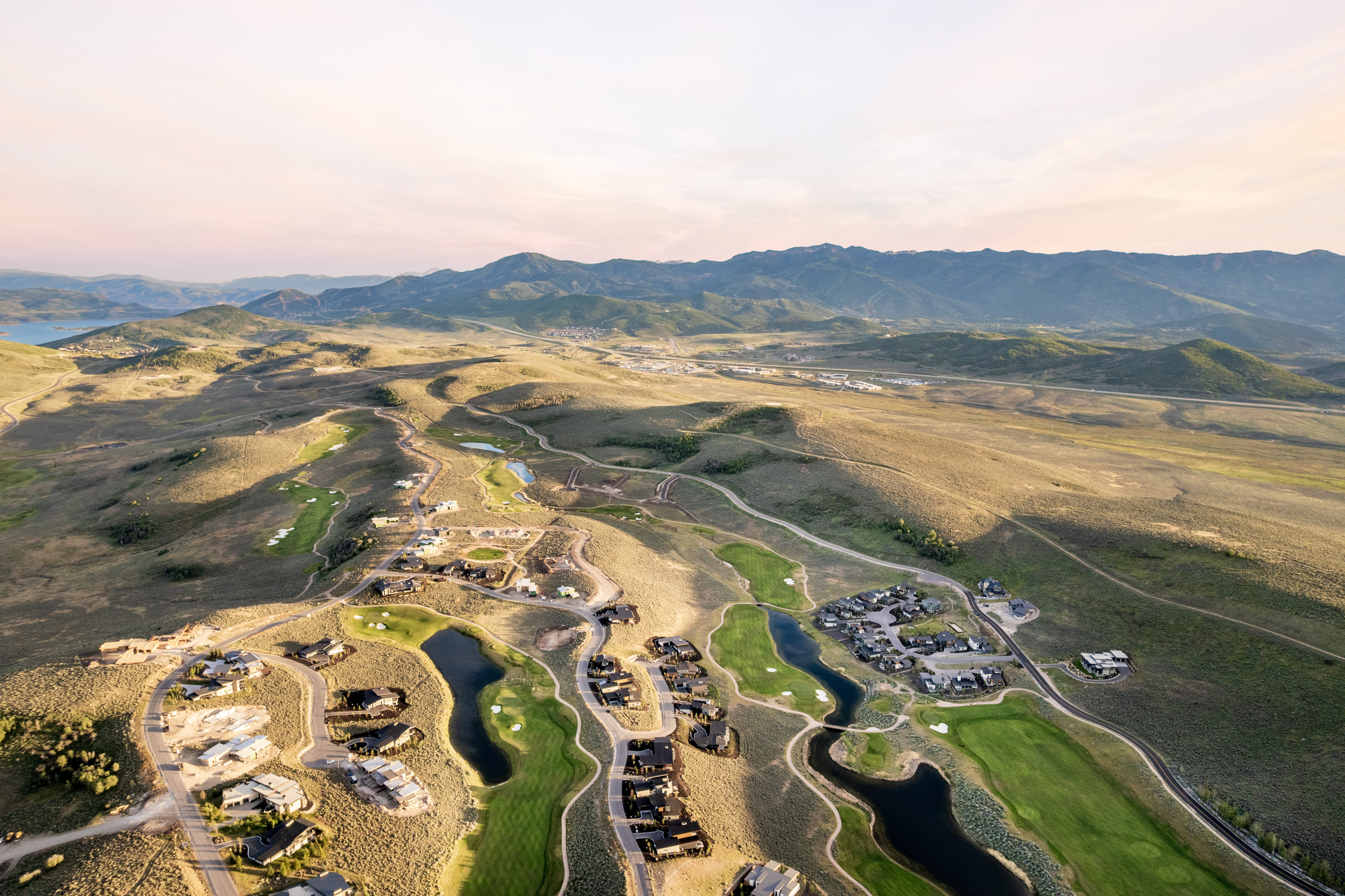 Expansive aerial view showcasing a golf course community with multiple homes, manicured greens, and water features