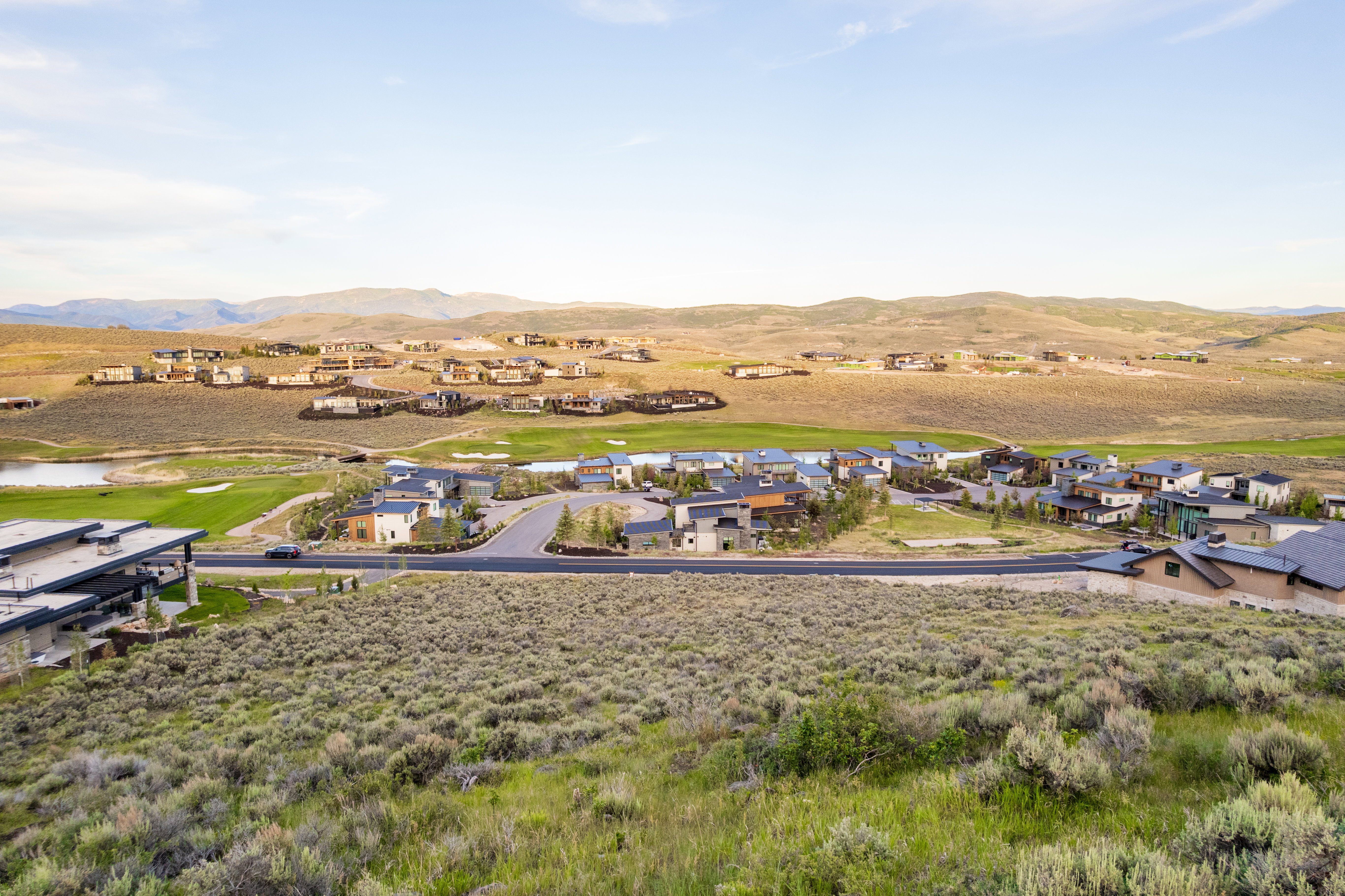 Expansive community featuring multiple residences, a golf course with water features, and surrounding hillsides
