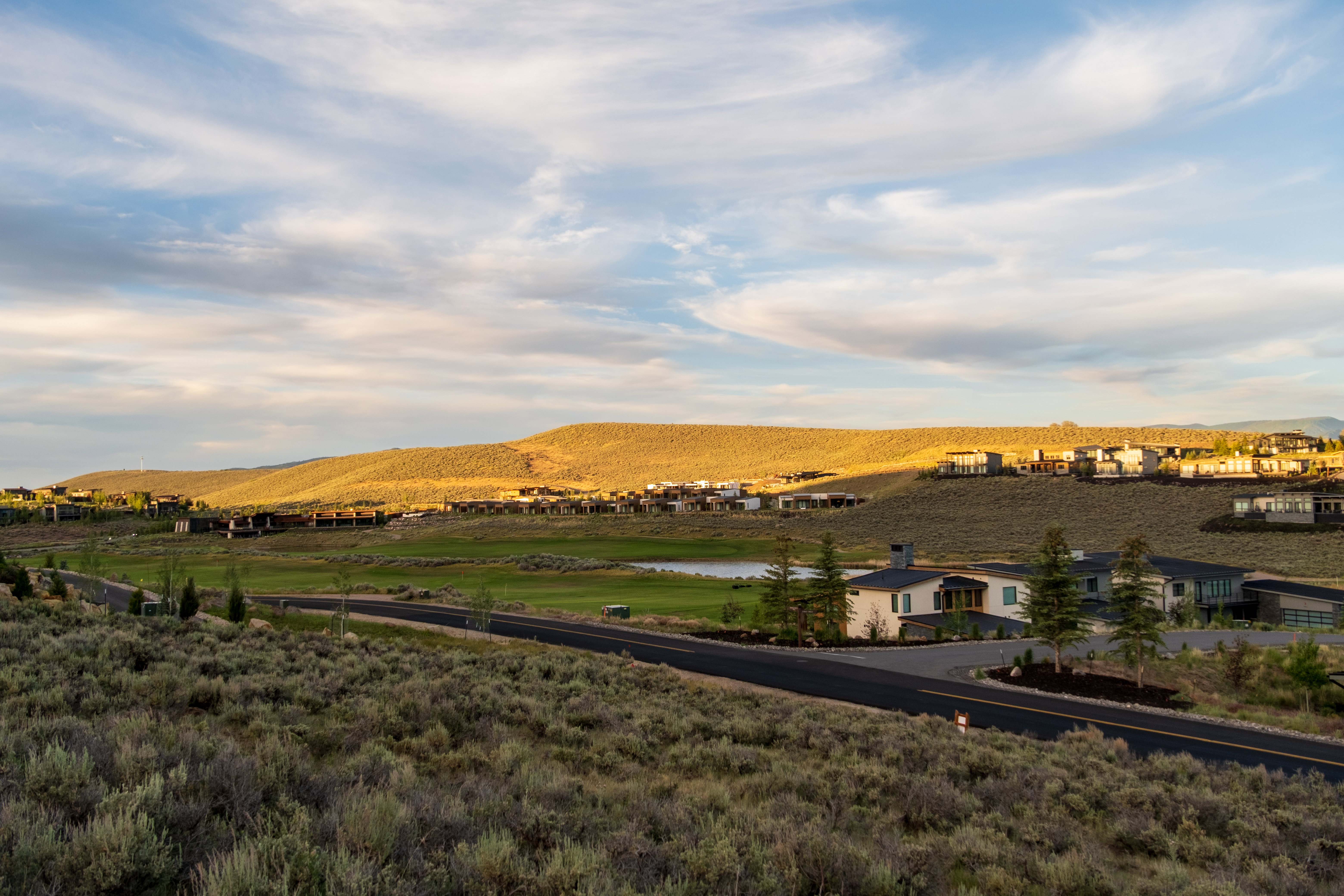 Rolling hillsides featuring established residences, a visible road, and a golf course