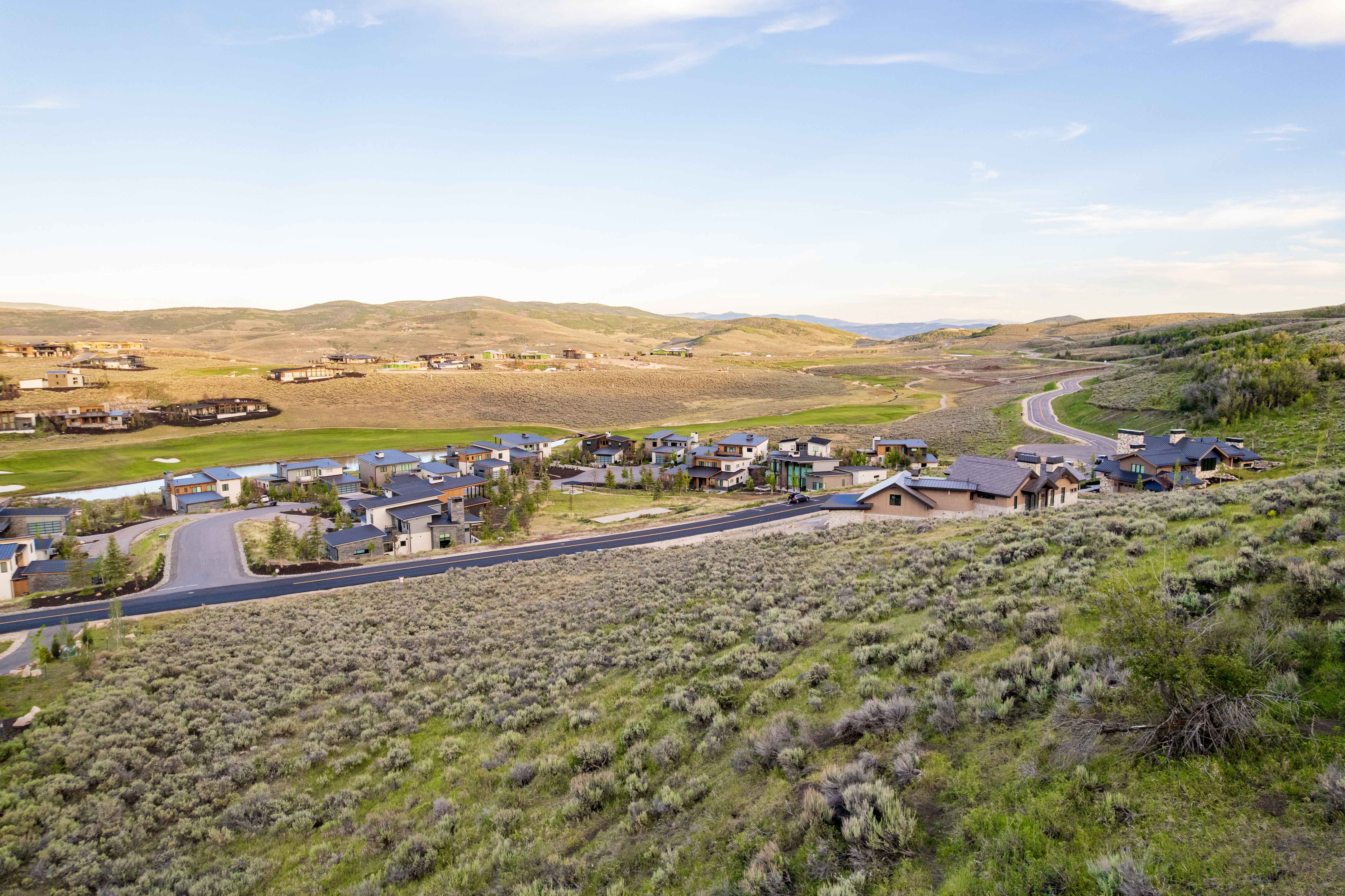 Expansive mountain landscape featuring a community of homes, paved roads, and natural vegetation