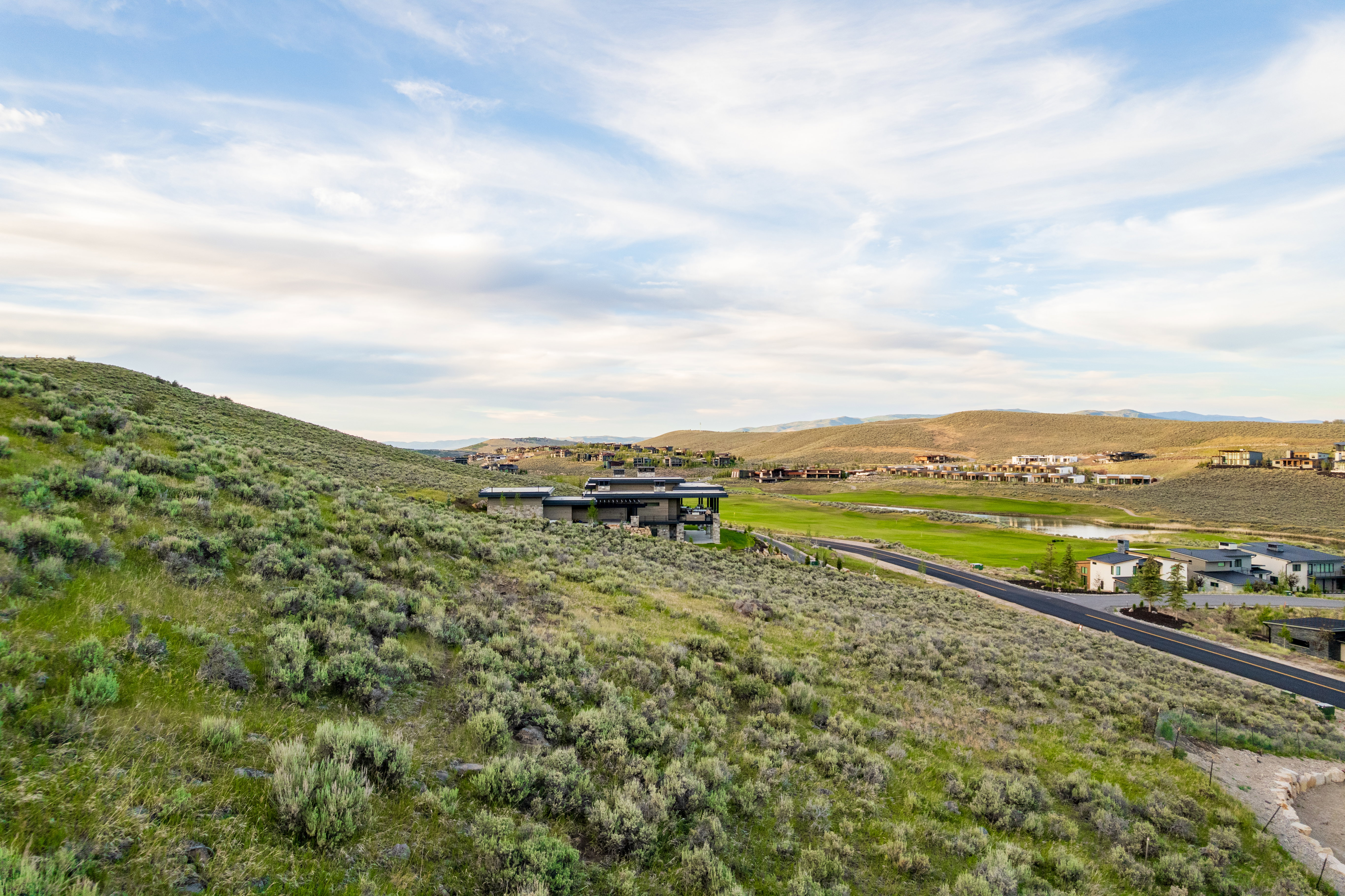 Expansive hillside property featuring natural shrubbery and a paved roadway