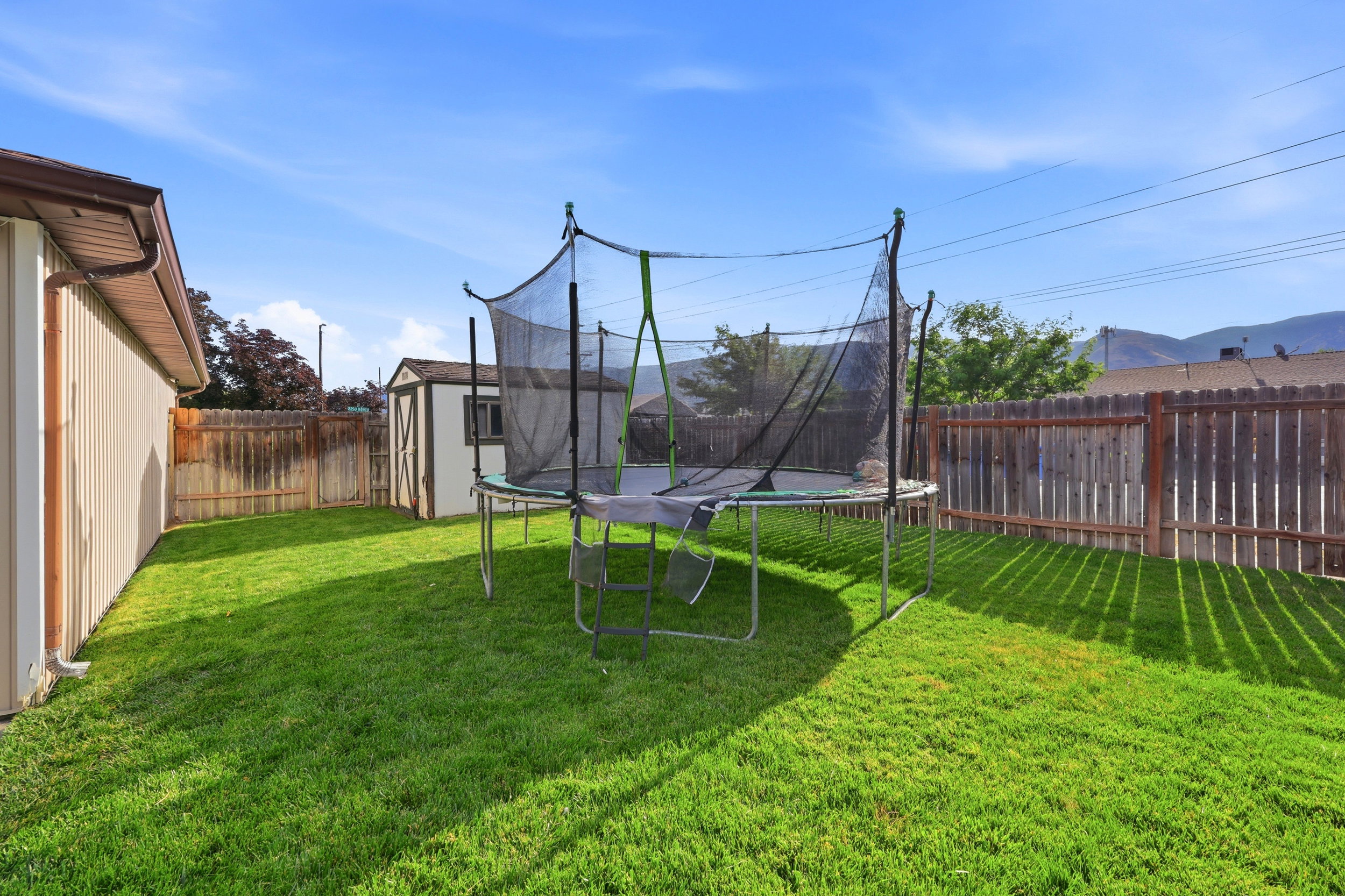 Spacious, fenced backyard featuring a manicured lawn, a detached storage shed, and a privacy fence