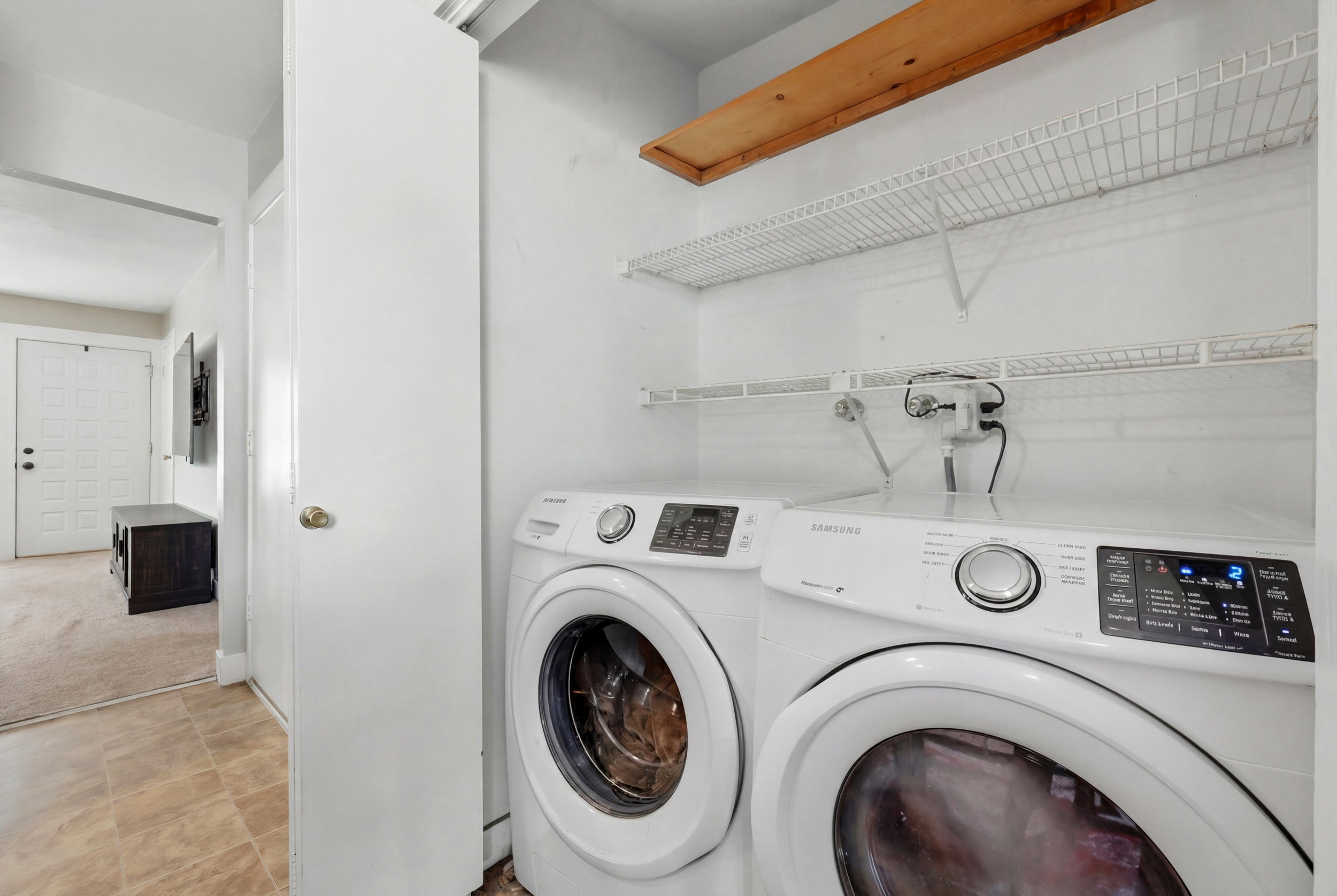 Dedicated laundry area featuring wire shelving, an overhead wood shelf, and light-toned flooring