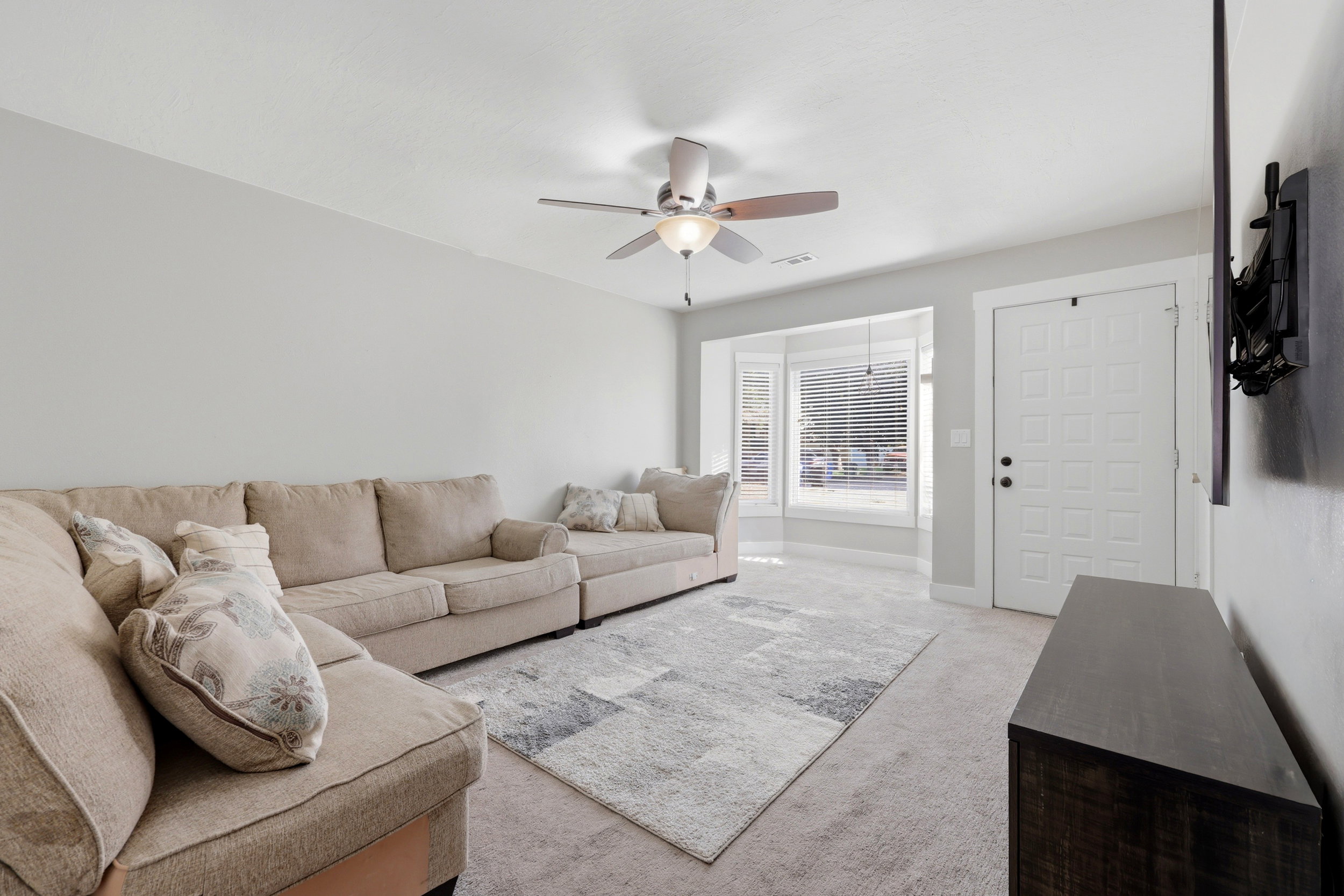 Living space featuring light gray wall paint, a ceiling fan with integrated lighting, and carpeted flooring