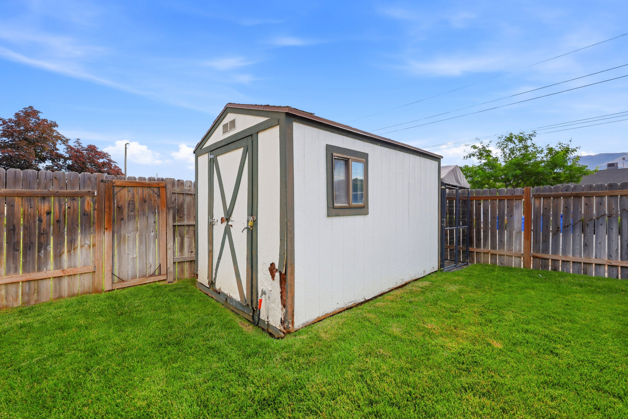 Exterior storage shed featuring a gable roof, a single window, and double entry doors