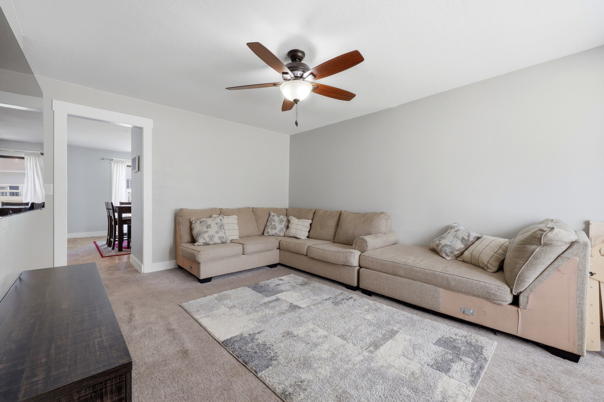 Carpeted living area featuring a ceiling fan with integrated lighting