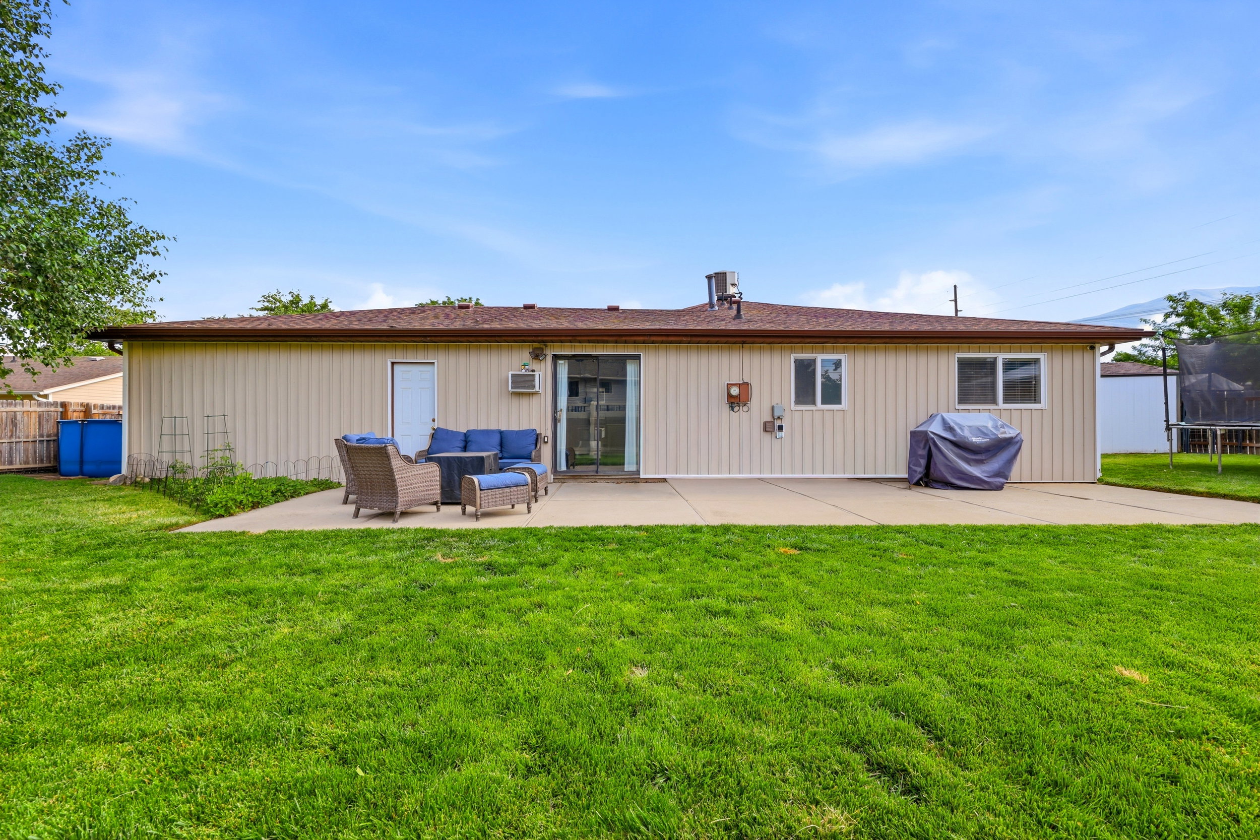Expansive backyard featuring a lush lawn, concrete patio, and neutral-toned siding