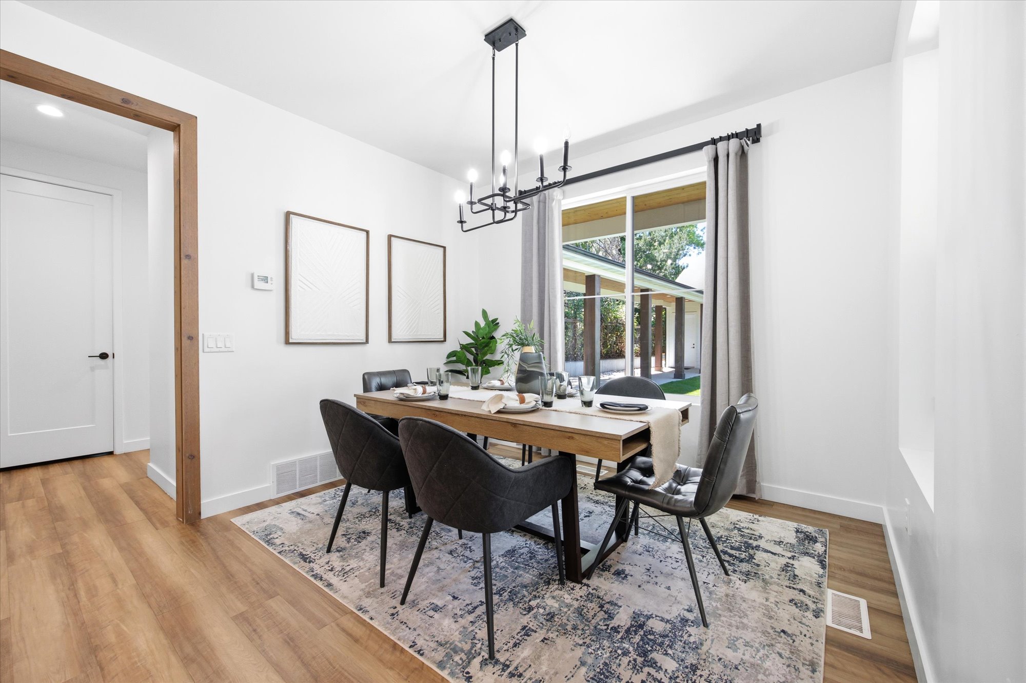 Dining area featuring wood-finish flooring, a contemporary chandelier, a large window with exterior views, and crisp white walls