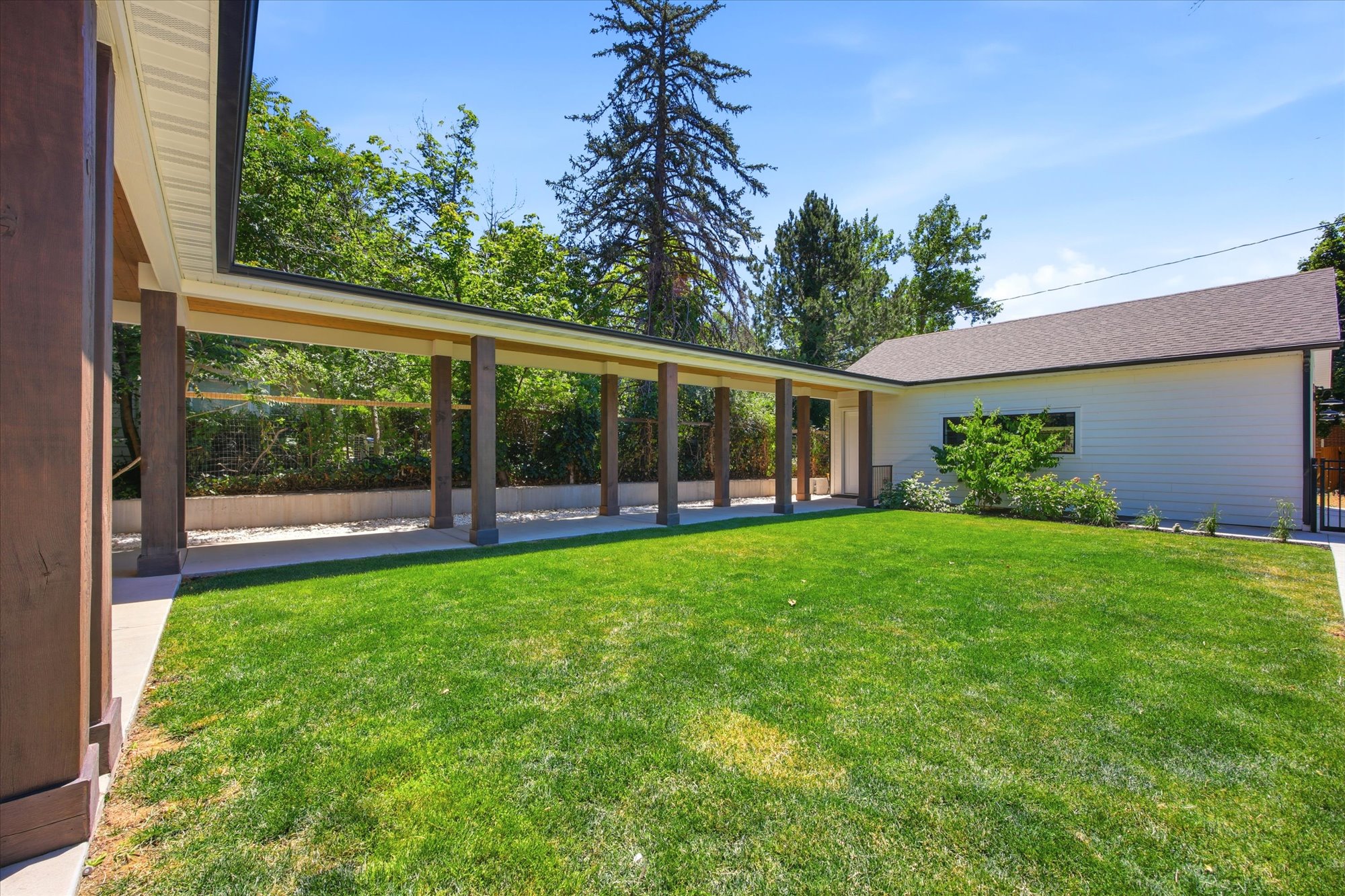 Expansive green lawn area with a covered walkway featuring multiple columns