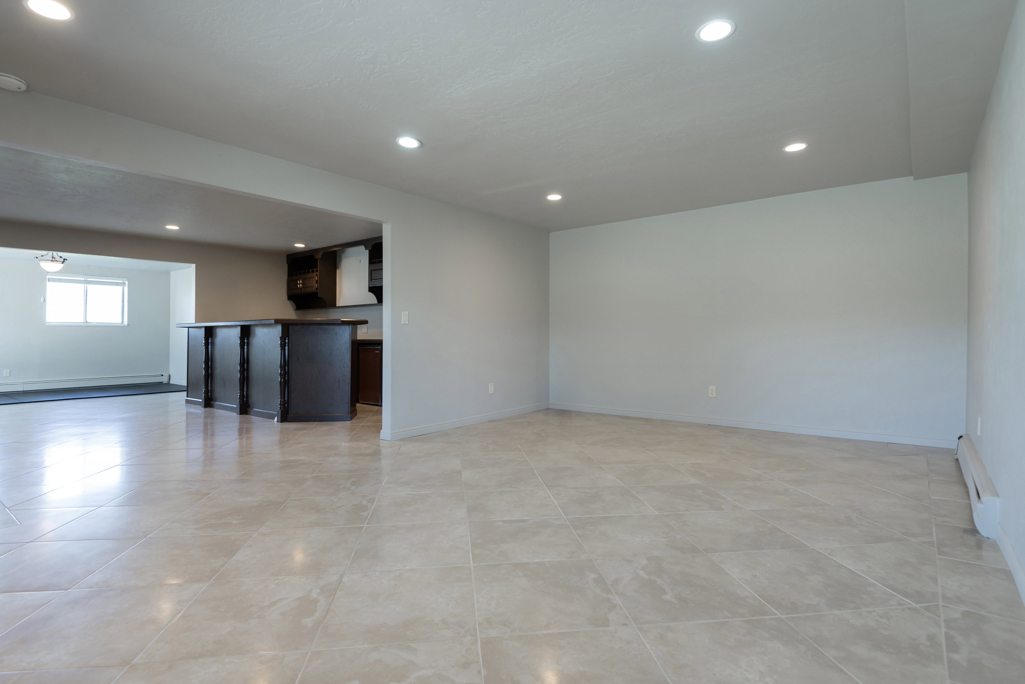 Spacious interior featuring large format tile flooring, recessed lighting, and a neutral color palette