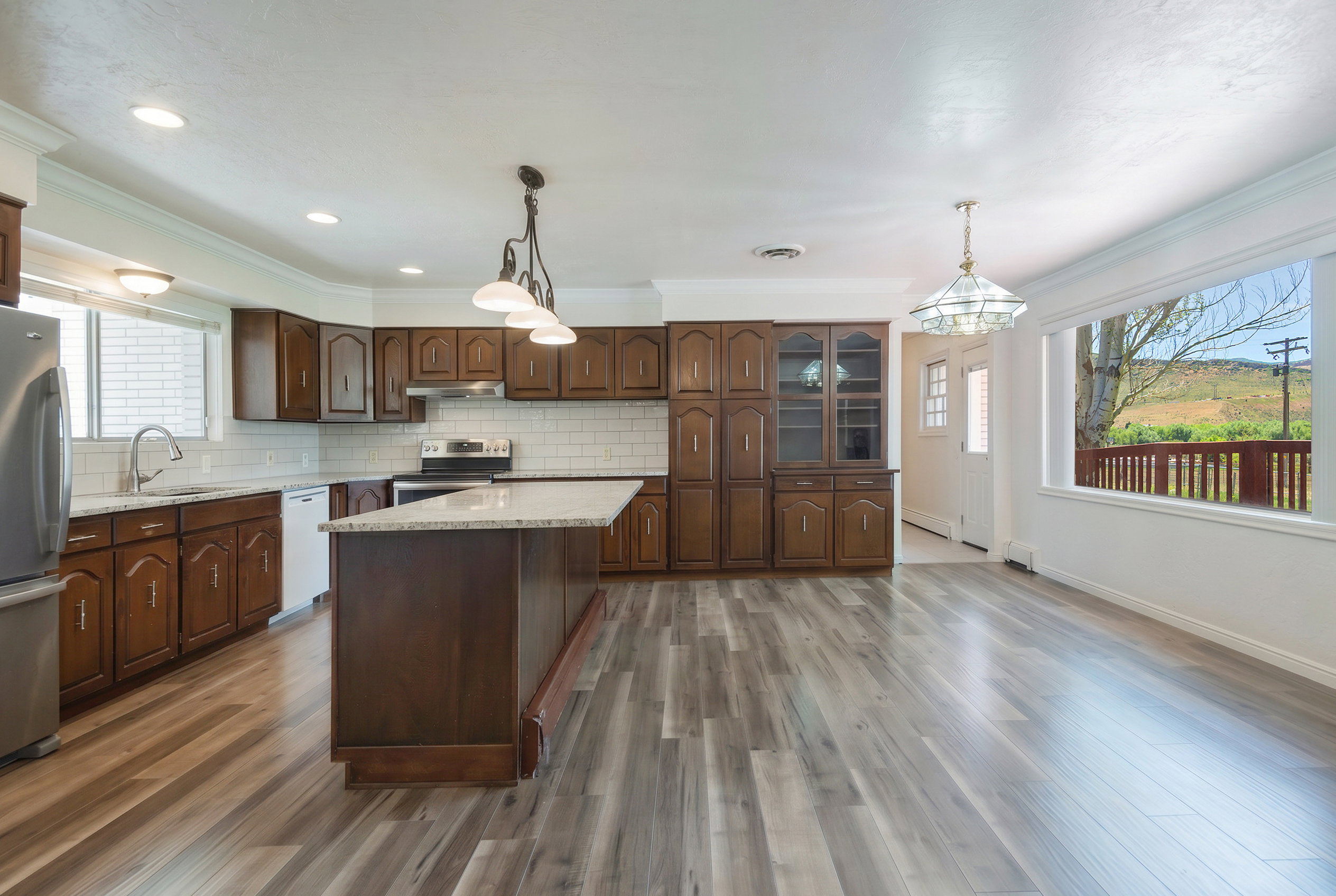 Open-concept kitchen and dining area featuring wood-finish flooring, recessed lighting, and a kitchen island with a light-toned countertop