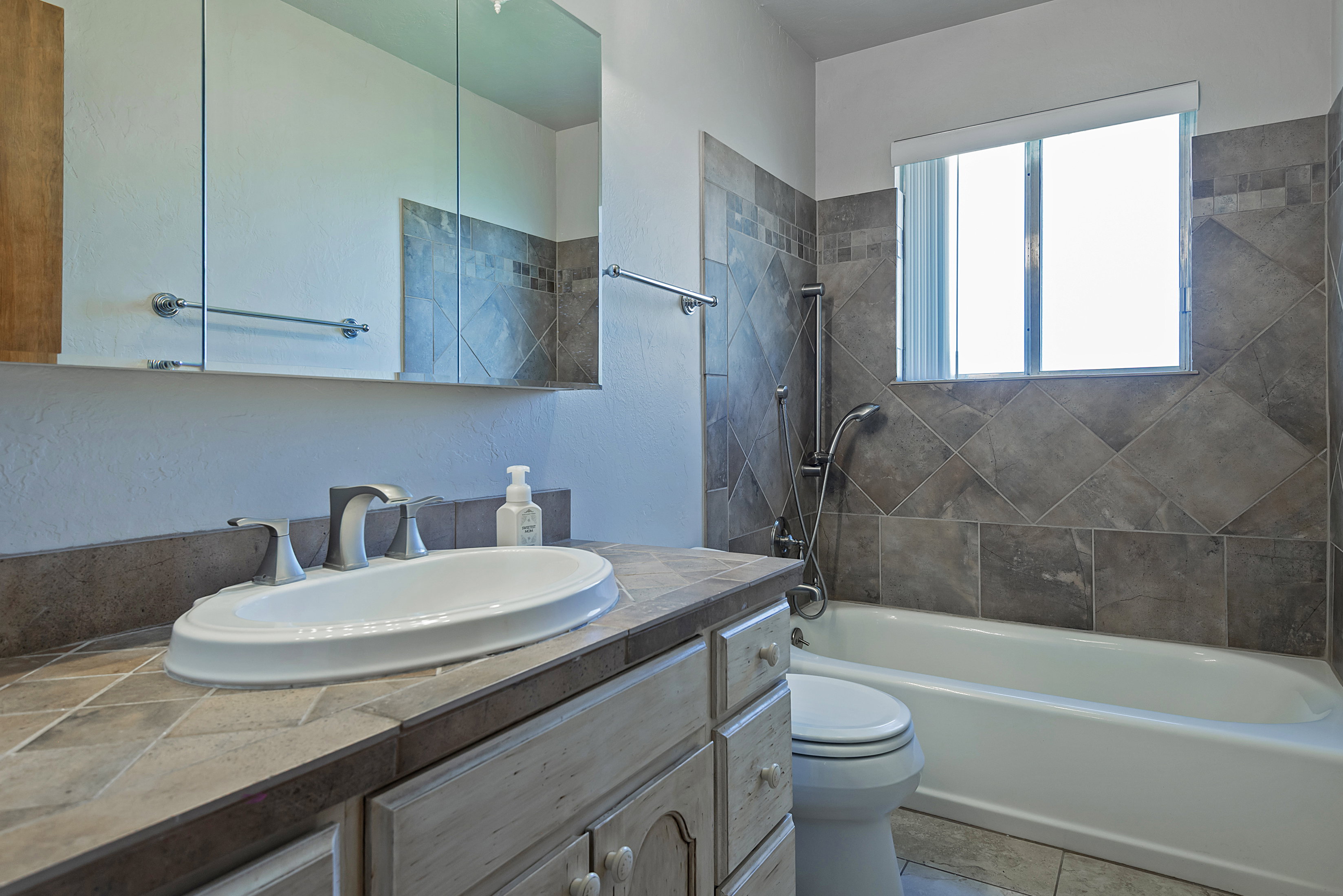 Bathroom featuring a single vanity with an integrated sink, brushed nickel faucet, and wood-finish cabinetry