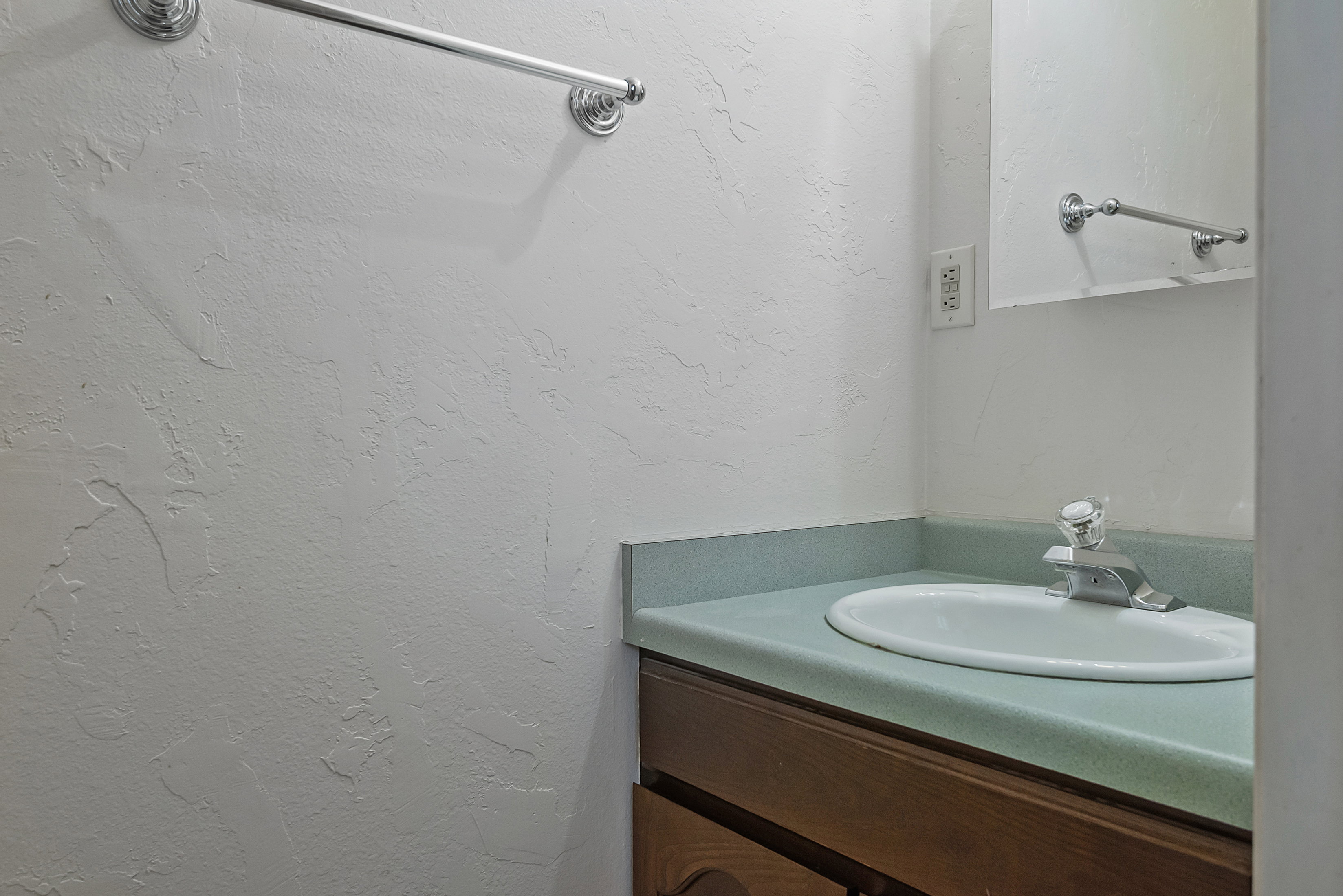 Vanity featuring a white oval sink, chrome faucet, and teal countertop