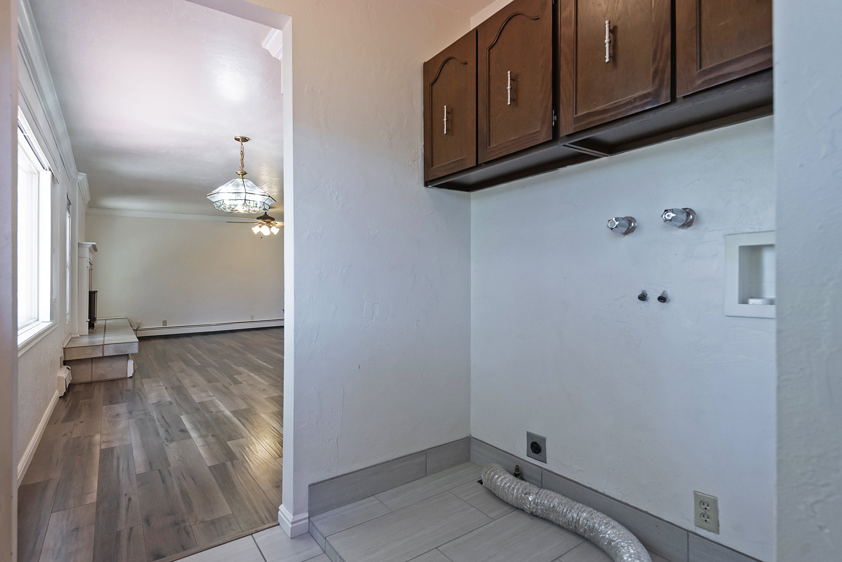 Dedicated laundry area featuring upper wood cabinetry and tile flooring