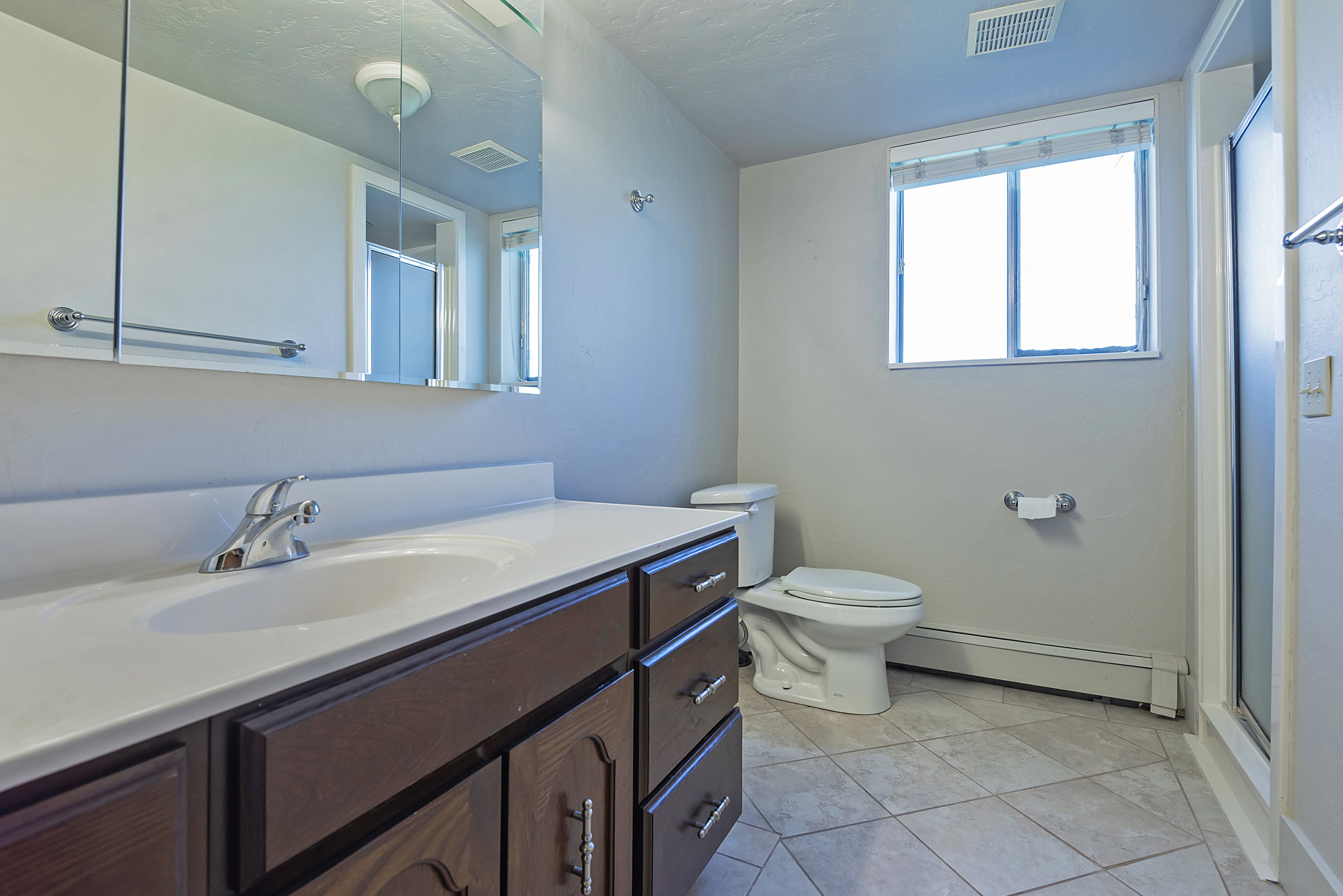 Bathroom featuring a dark wood-finish vanity with an integrated white sink, a chrome faucet, and a large wall-mounted medicine cabinet