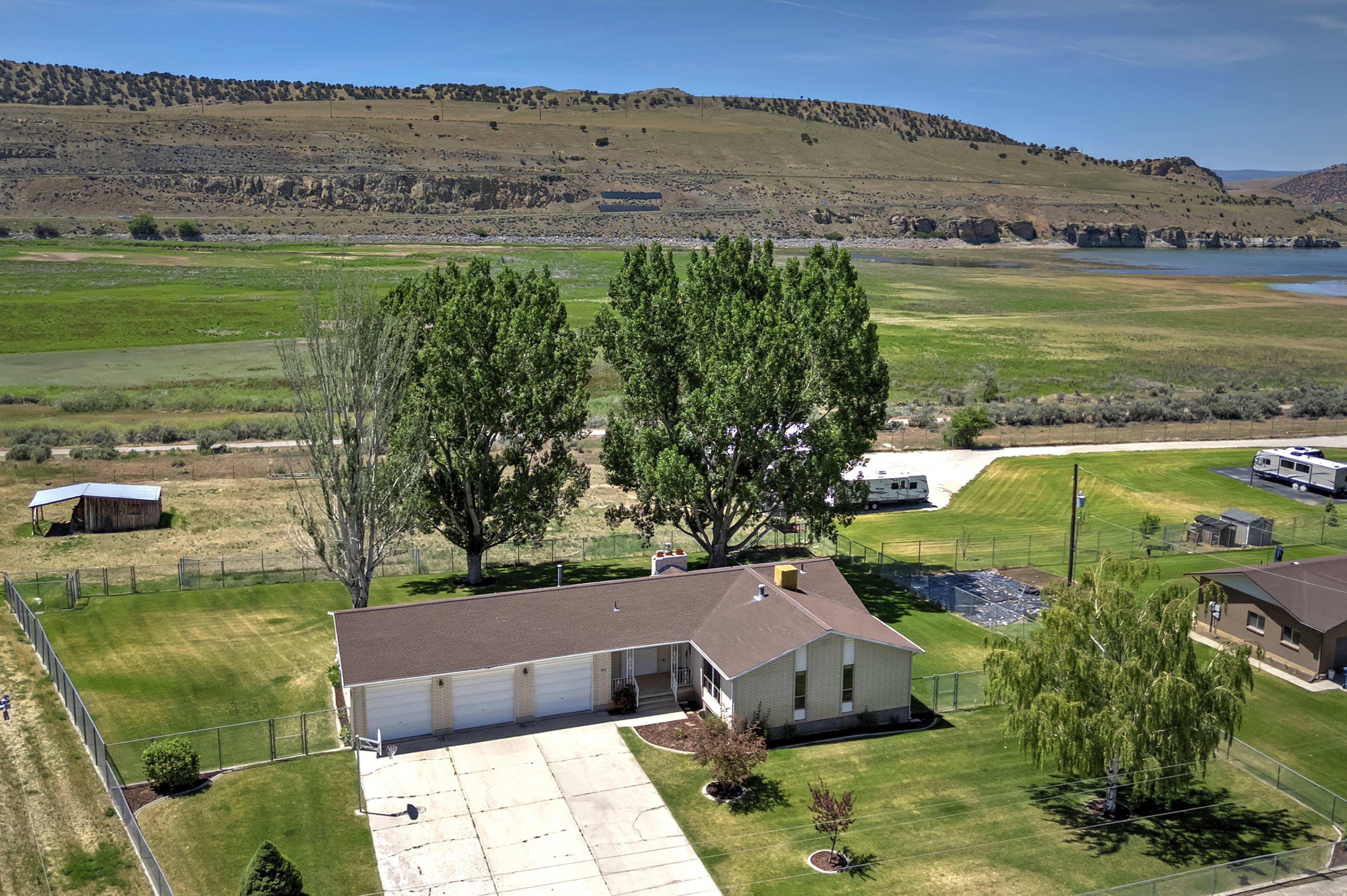 Expansive property featuring a ranch-style home with a three-car garage, established landscaping, and a fenced yard