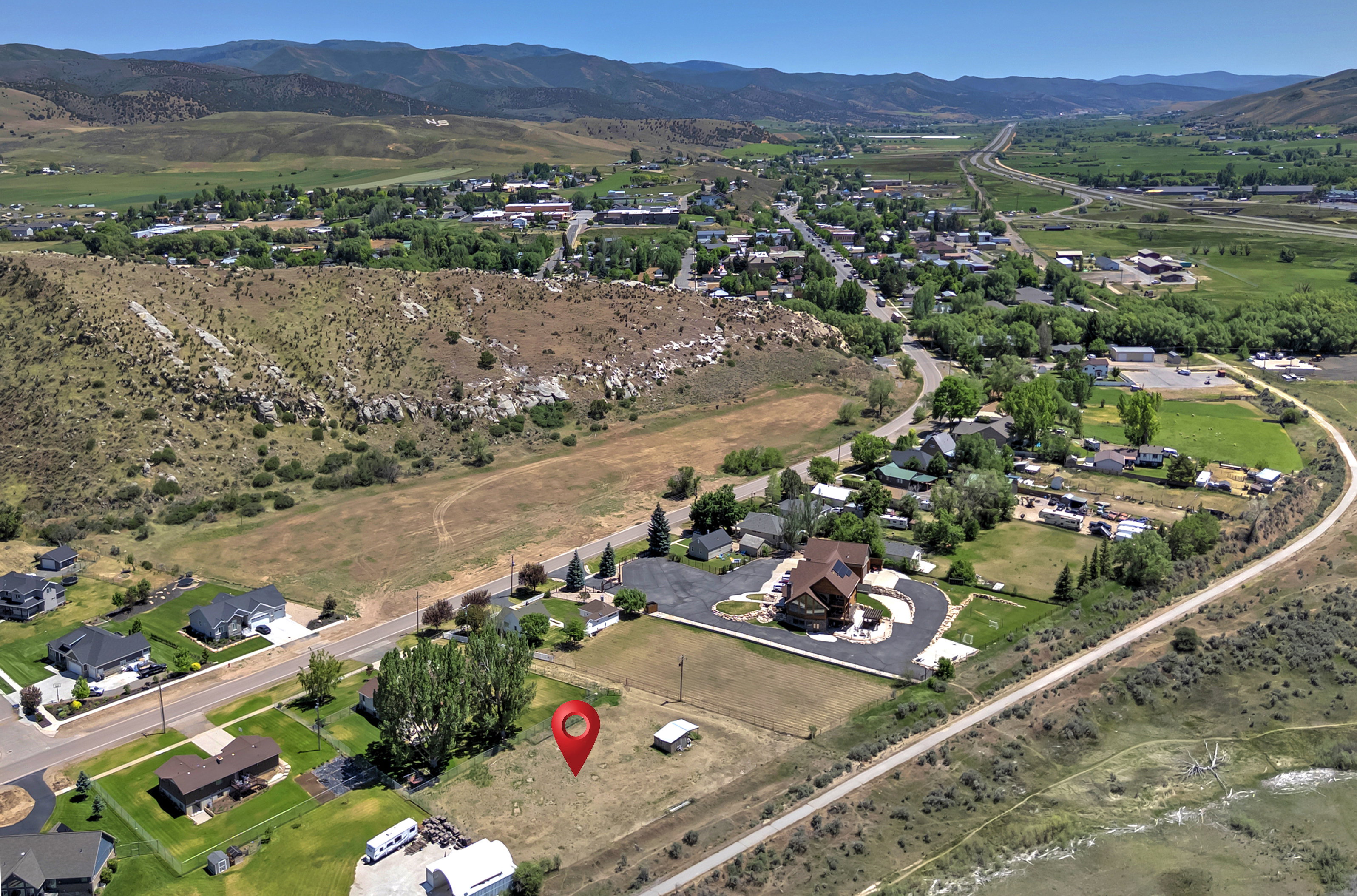 Expansive land parcel with surrounding residential properties, paved roads, and natural hillsides