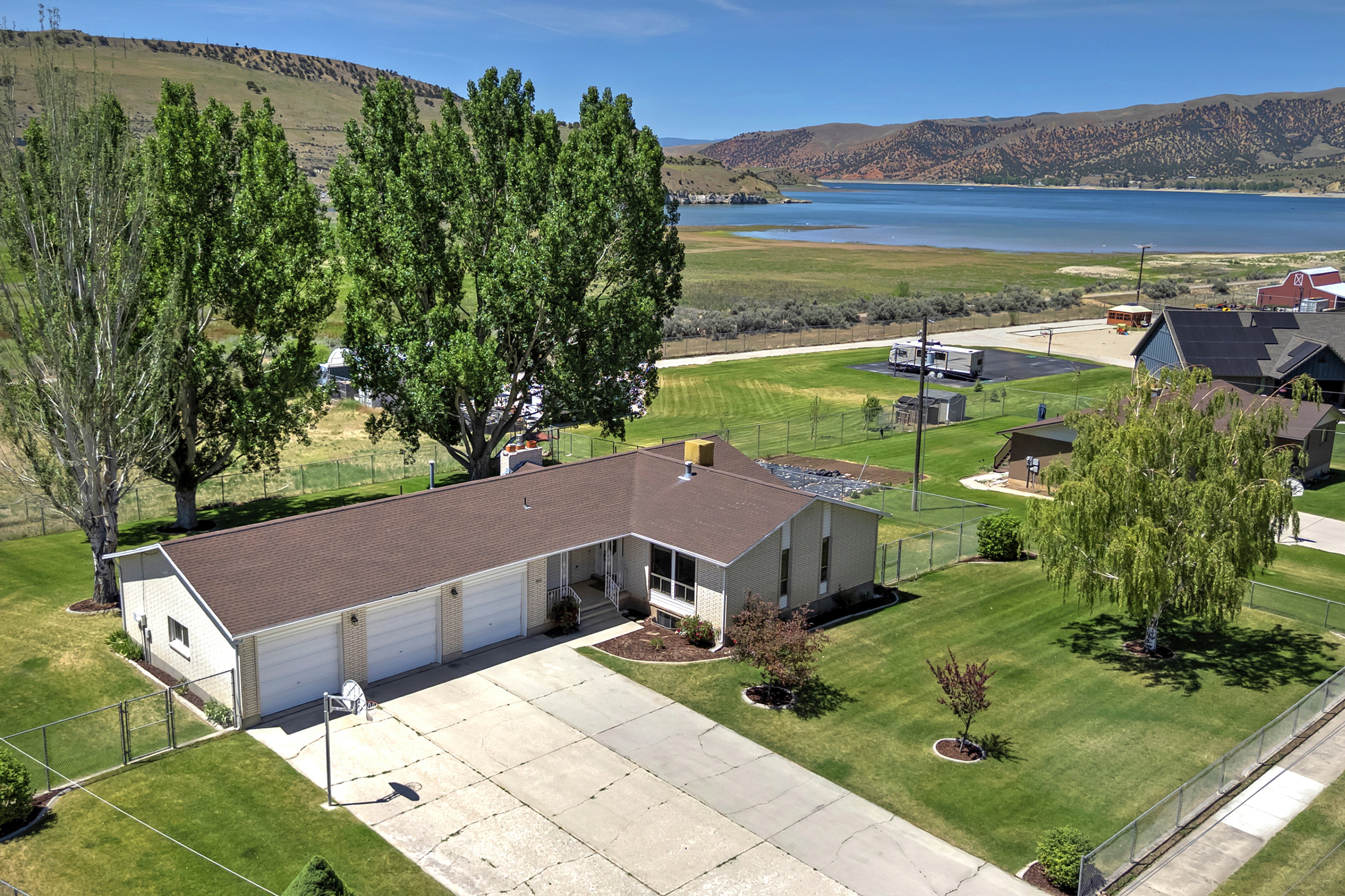 Ranch-style residence featuring a three-car garage, expansive concrete driveway, and a verdant lawn