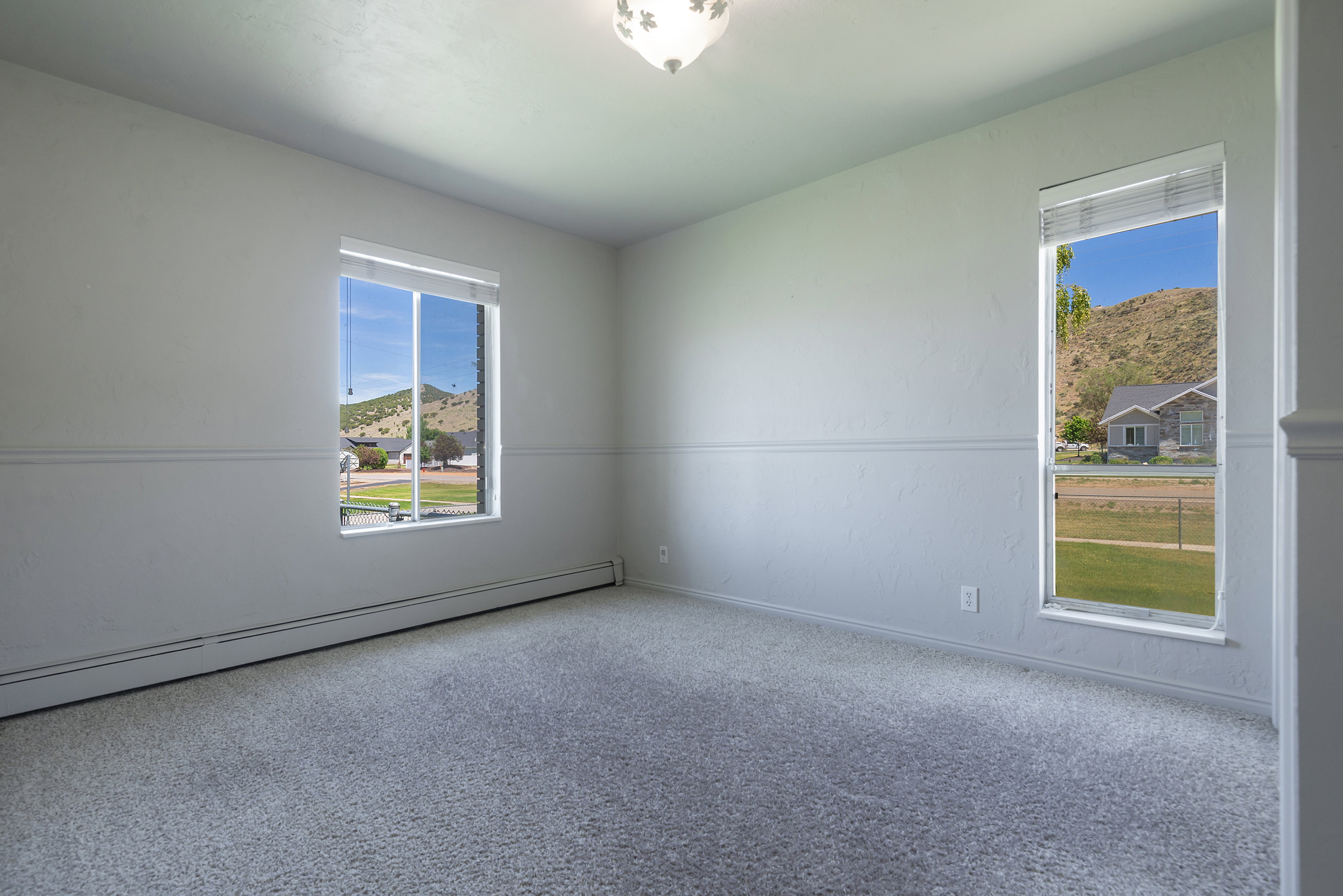 Carpeted room featuring multiple windows, chair rail molding, and a ceiling-mounted light fixture