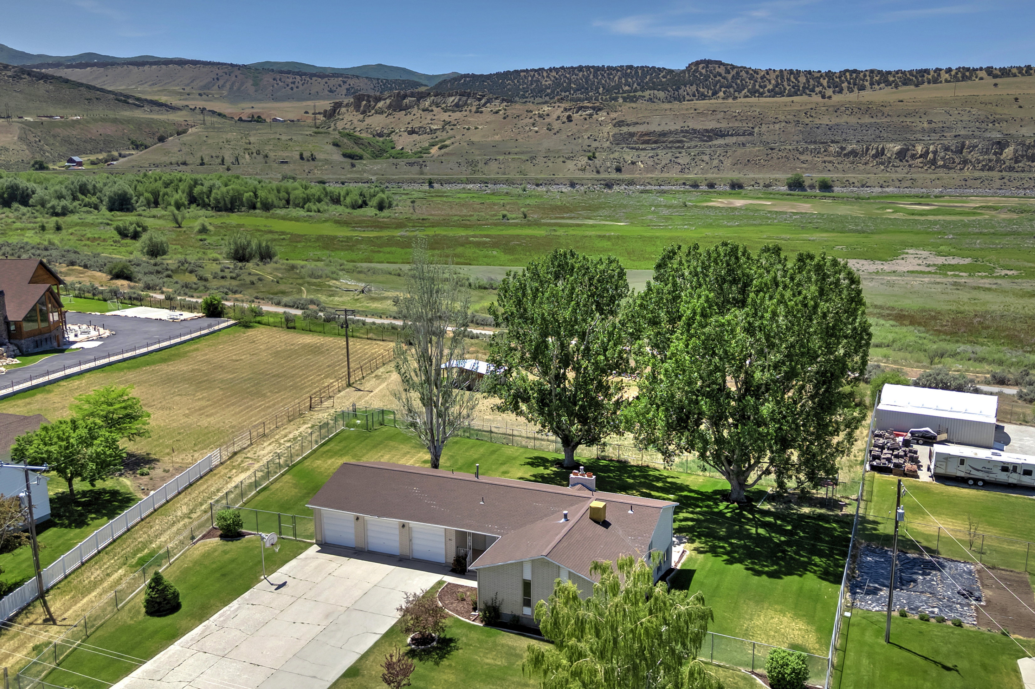 Ranch-style residence featuring a three-car garage, expansive concrete driveway, and mature landscaping