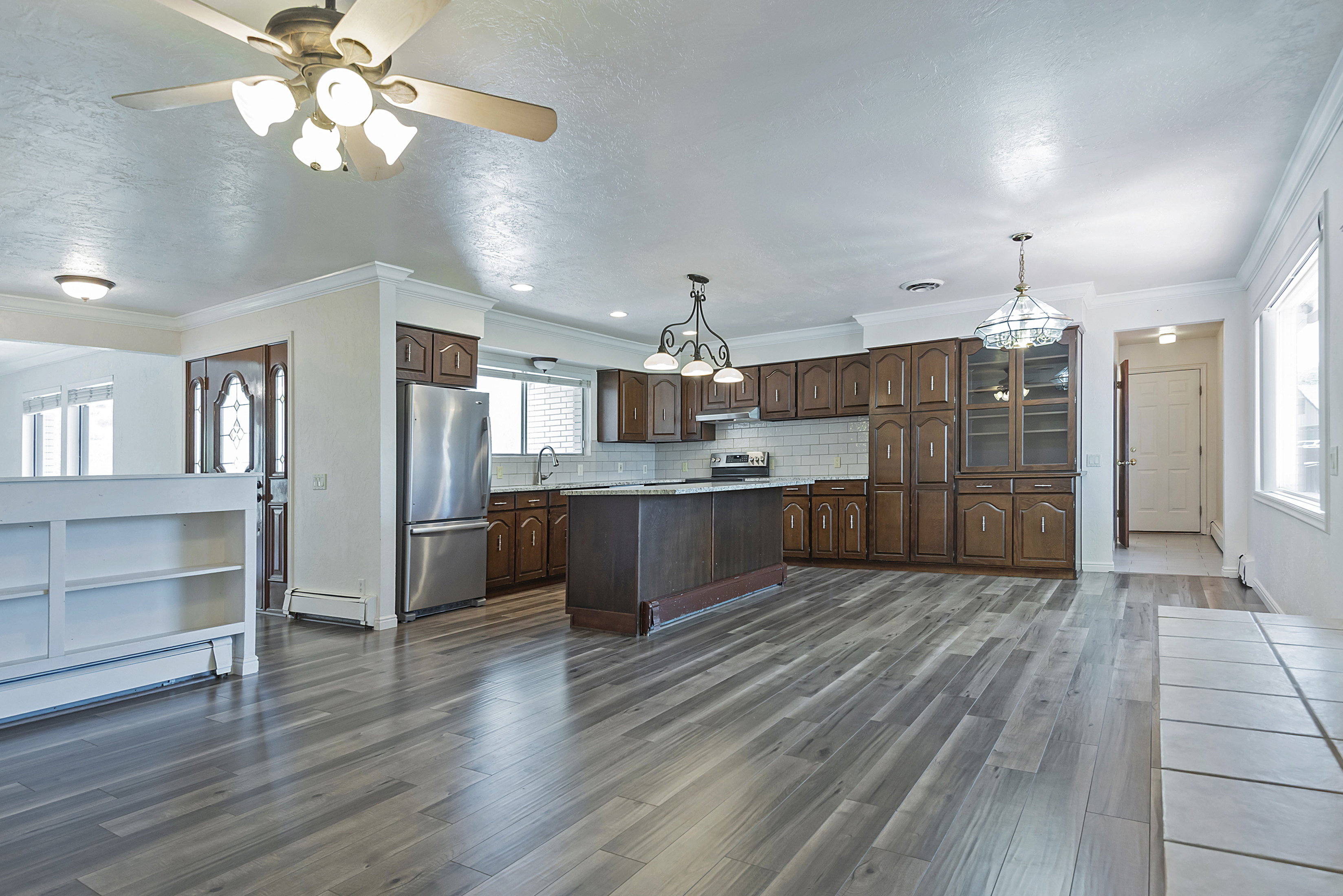 Open-concept kitchen and living area featuring wood-finish flooring, recessed lighting, and a ceiling fan