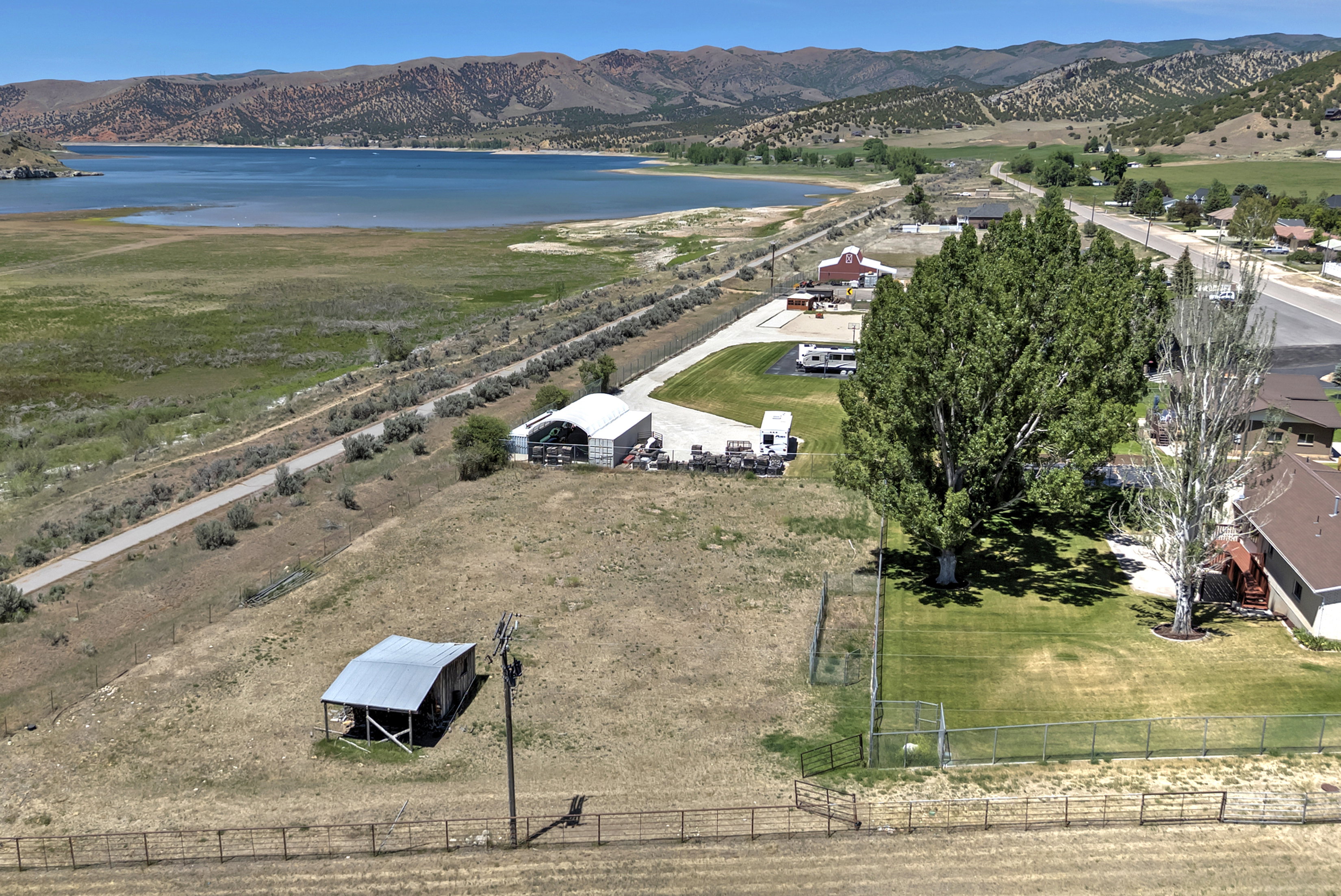 Expansive land parcel featuring a metal-roofed shed, a fenced grassy area, and a paved road