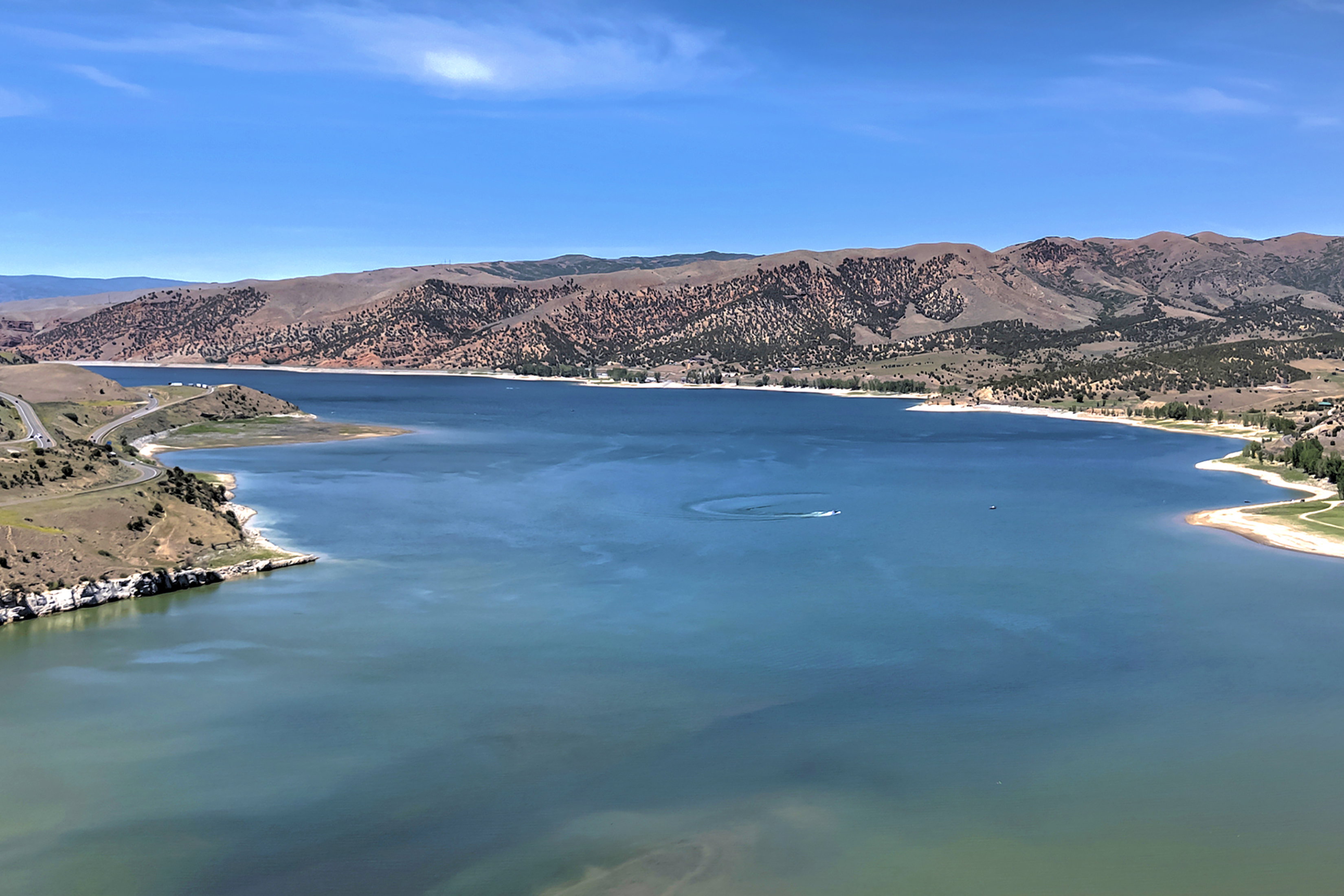 Expansive waterfront property featuring a large body of water, distant mountains, a meandering shoreline, and natural terrain